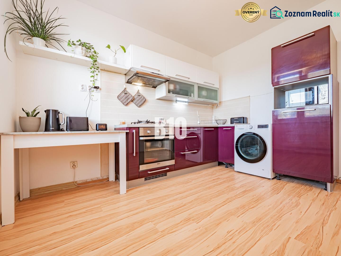 A kitchen with white shelves, a modern countertop, and a wooden decor floor in a studio apartment.