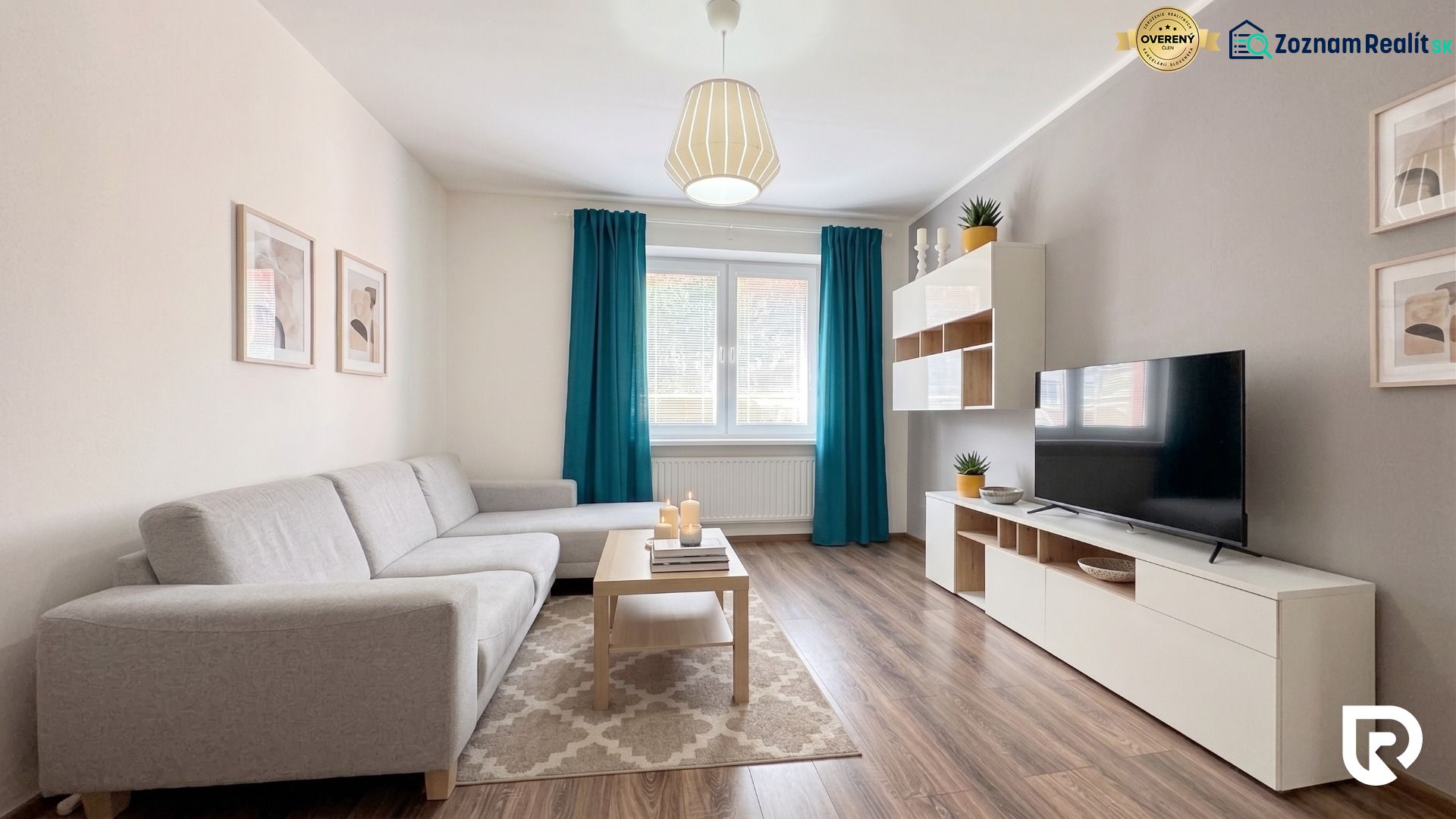Living room in a two-room apartment with a wooden decor floor and a gray sofa.