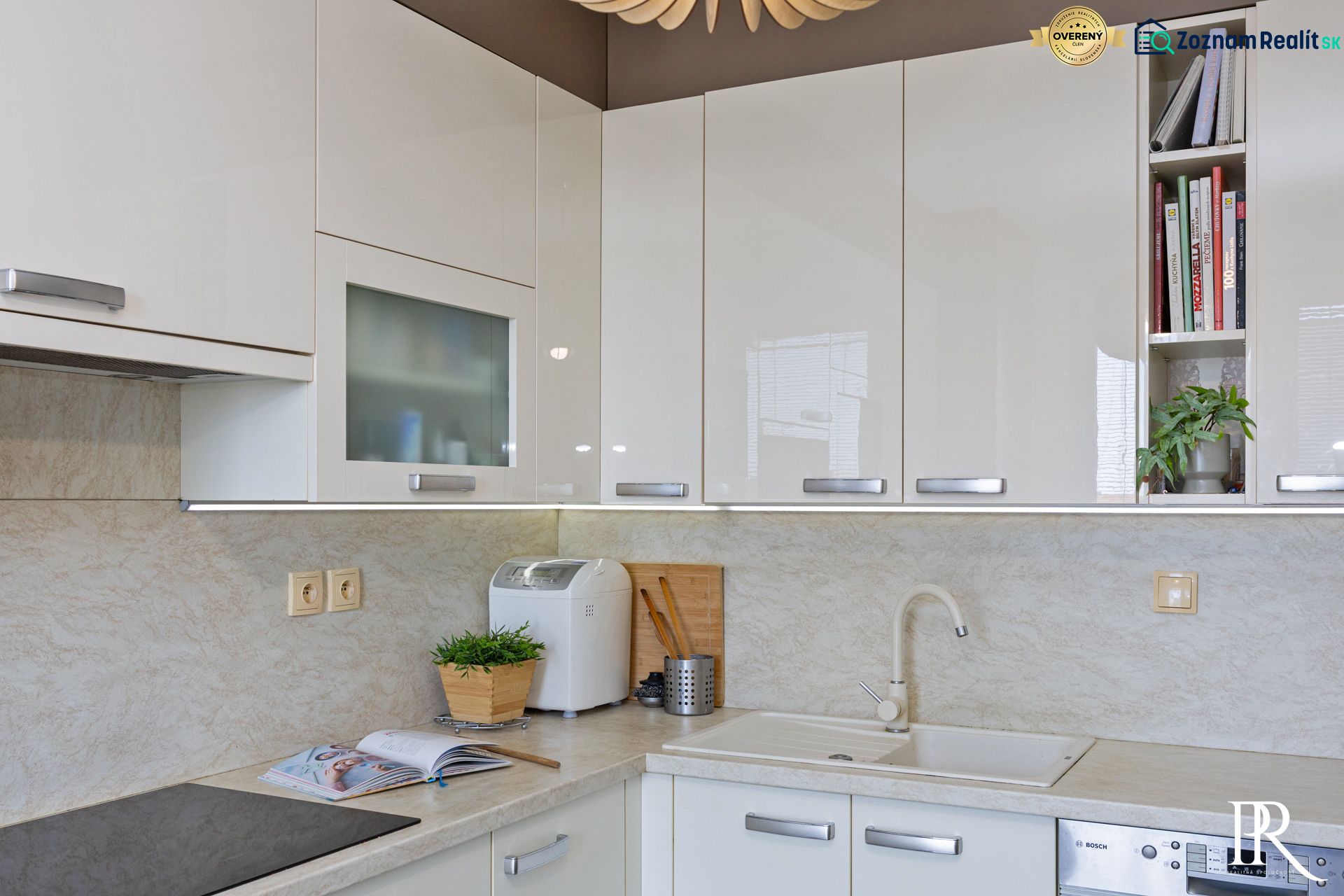A kitchen in a 3-room apartment with white glossy cabinets and built-in appliances.