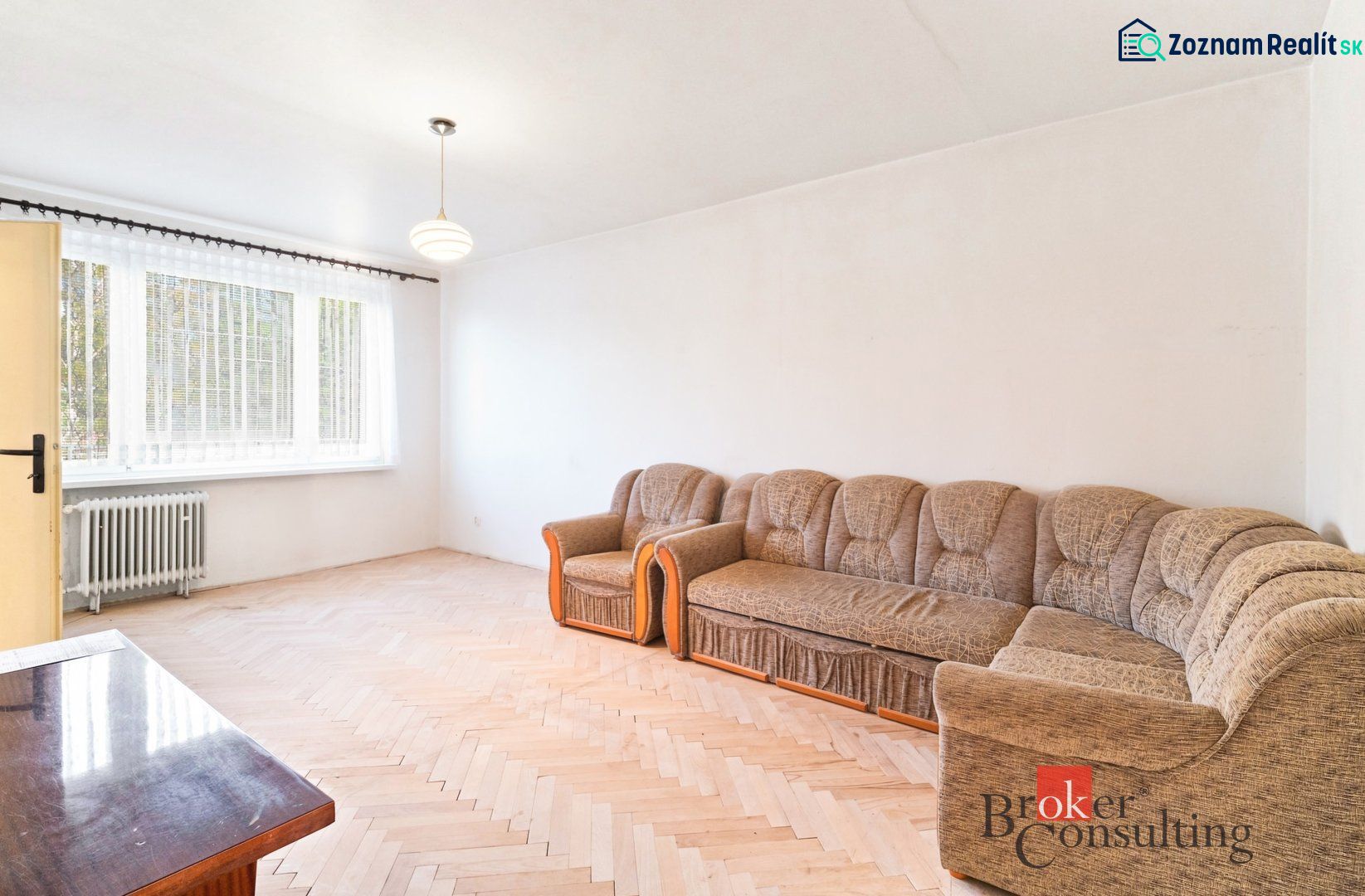 Living room in a two-room apartment with a wooden decor floor and a sofa.