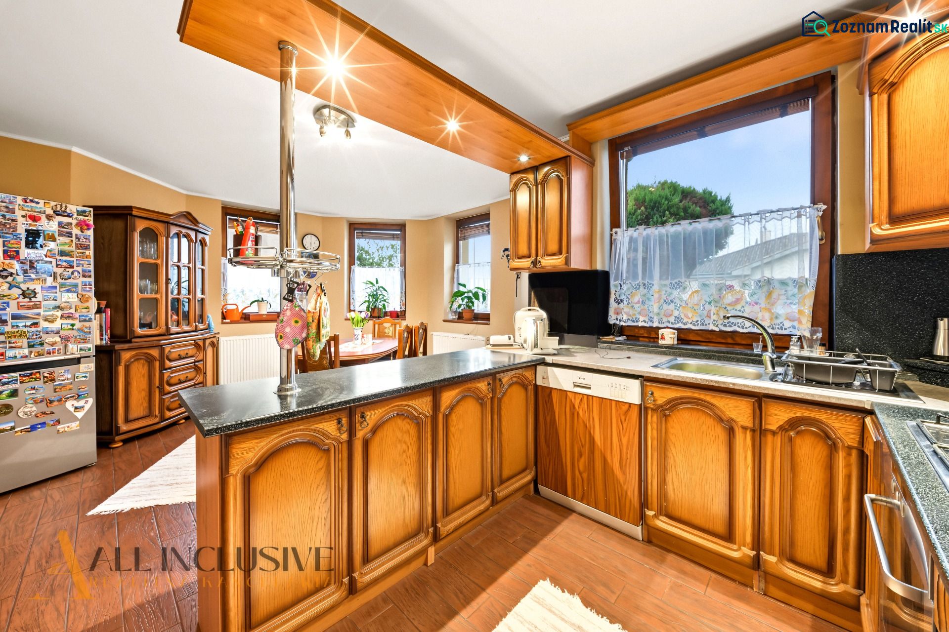 Traditional kitchen in a family house with wooden cabinets and a large window.