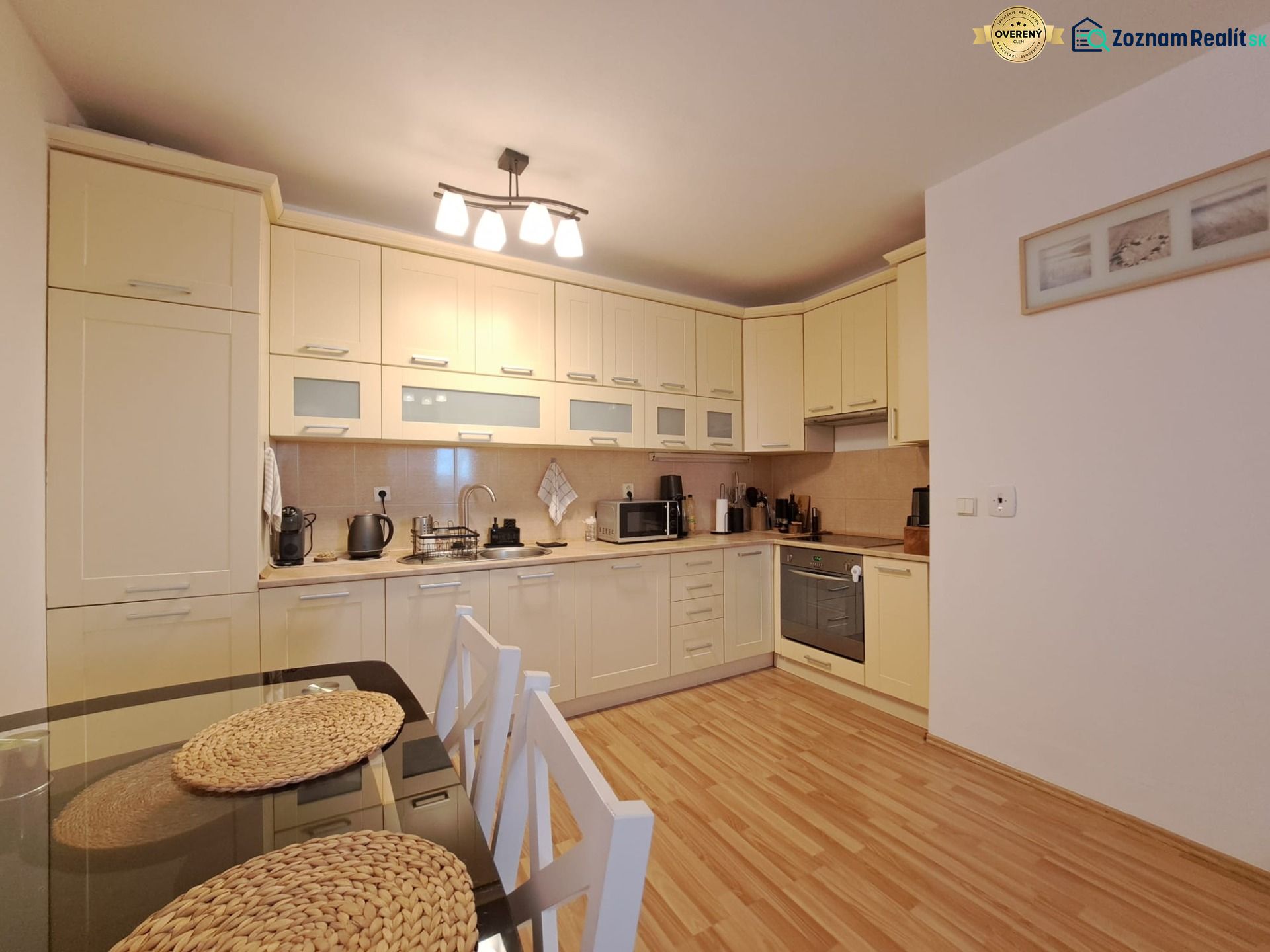 A kitchen in a 2-room apartment with a wooden decor floor and a dining table.