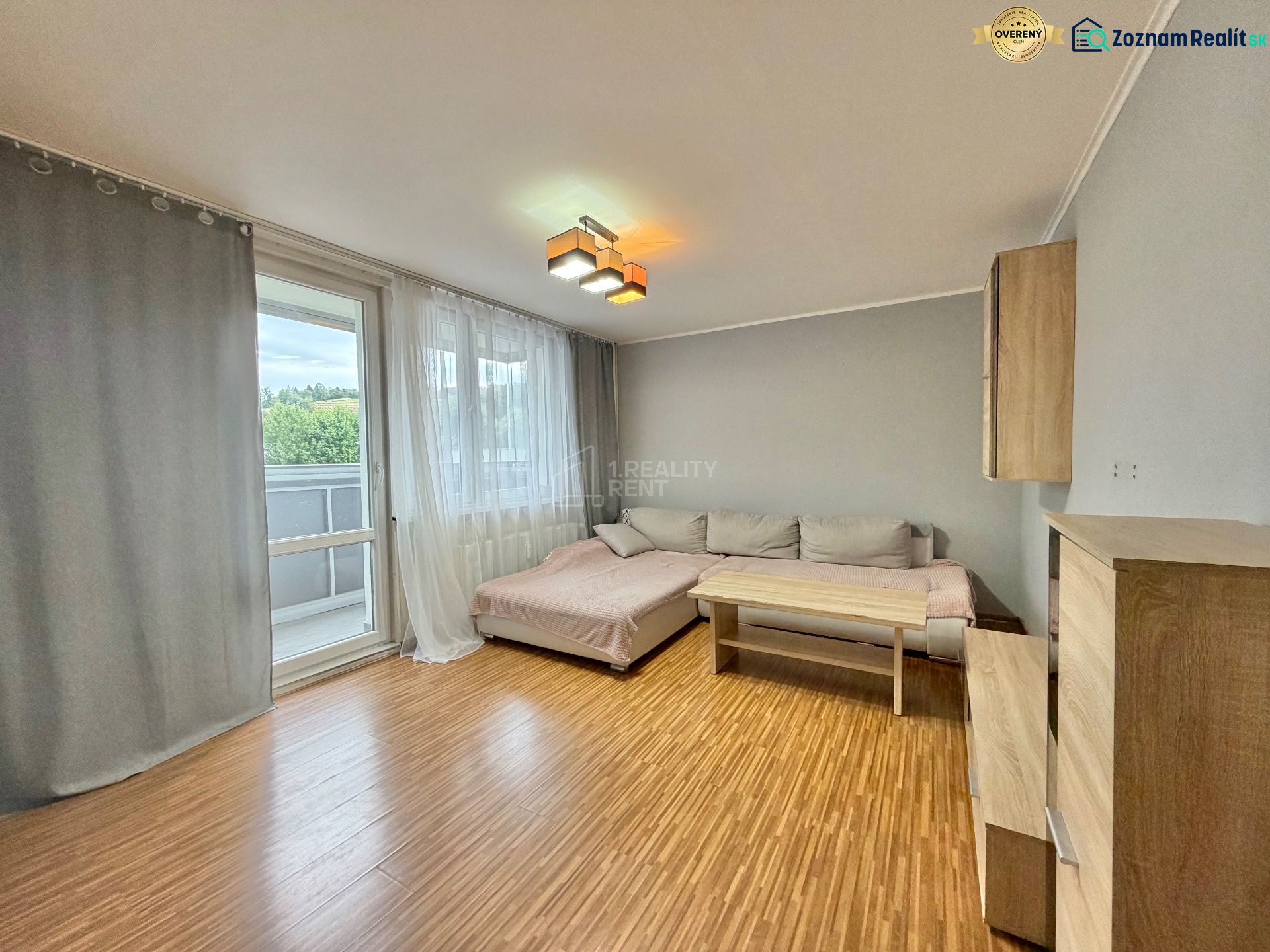 Living room in a three-room apartment with a wooden decor floor and a sofa.