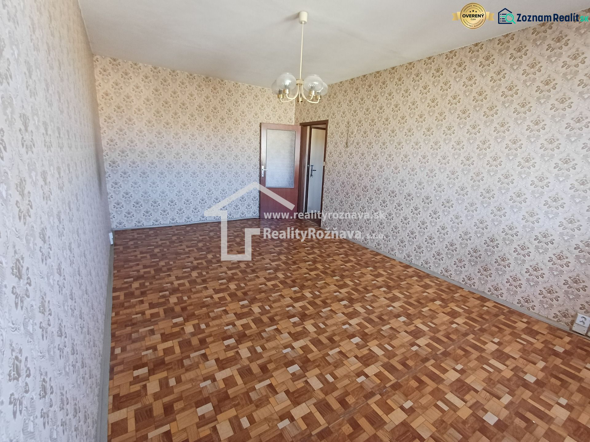 Wallpaper with a floral pattern and a floor with a wooden design in a studio apartment.