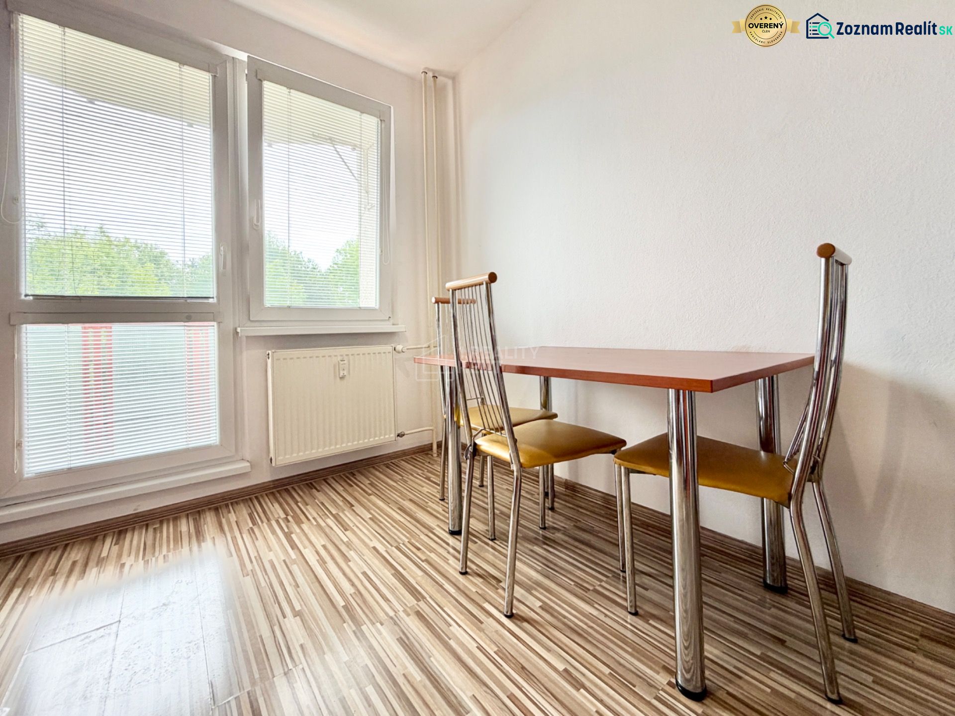 Dining room with wood-patterned flooring, table, and chairs in a two-room apartment.