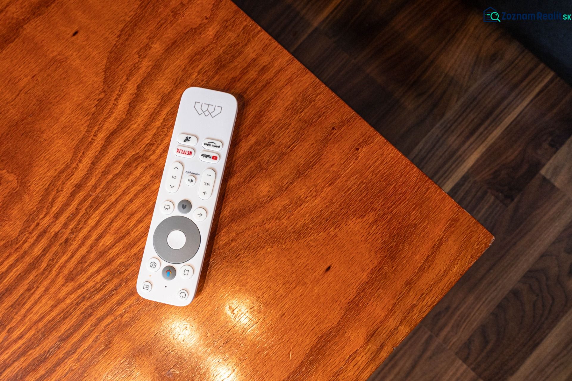 A remote control on a wooden table, next to a floor with wooden decor in a 2-room apartment.