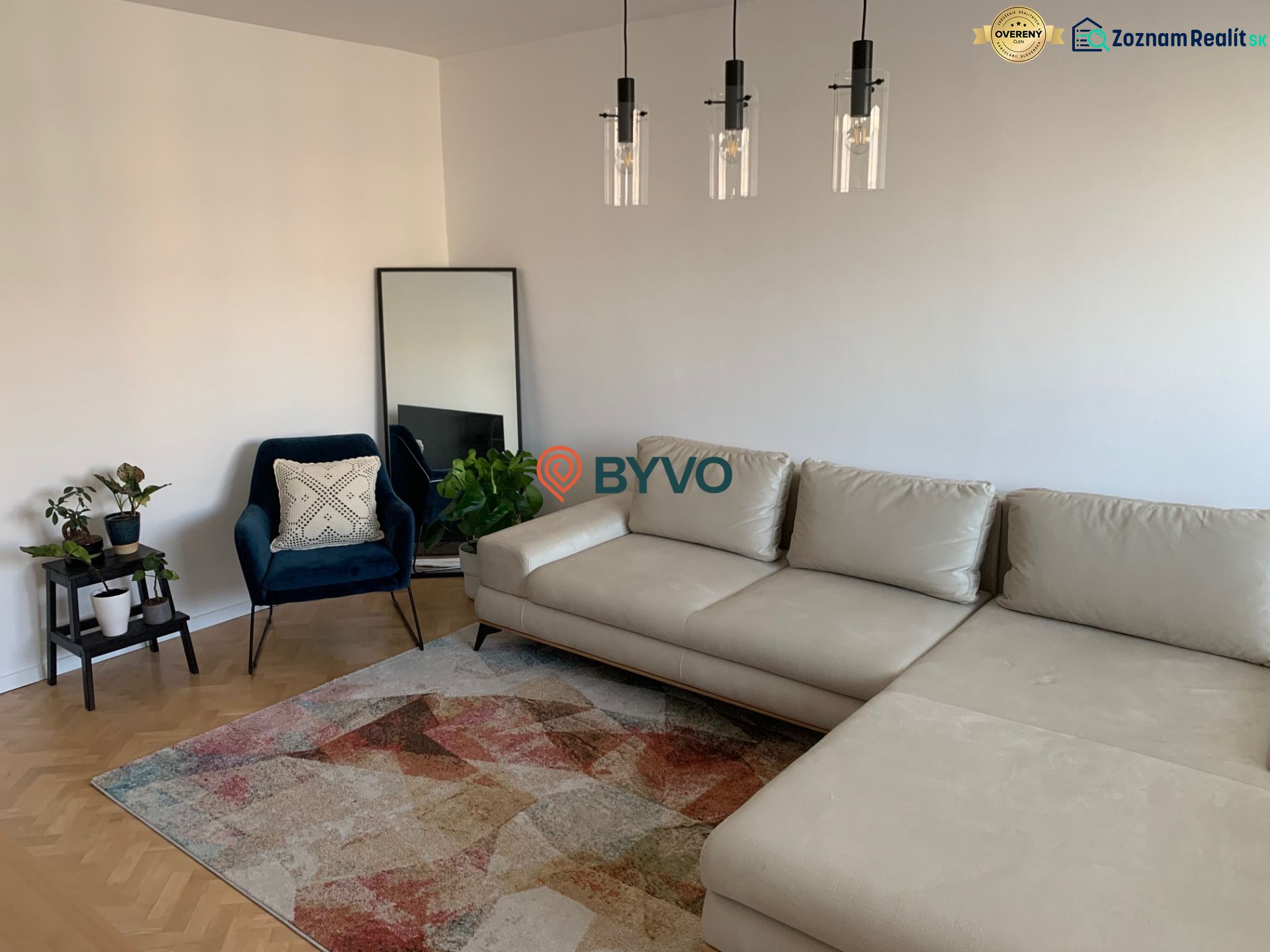 Living room in a two-room apartment with a sofa, an armchair, and a wooden decor floor.