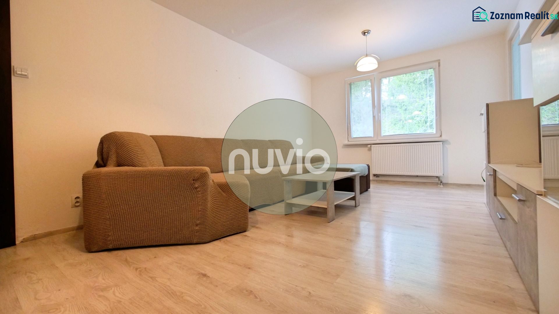 Living room with a sofa and wood-patterned flooring in a three-room apartment.
