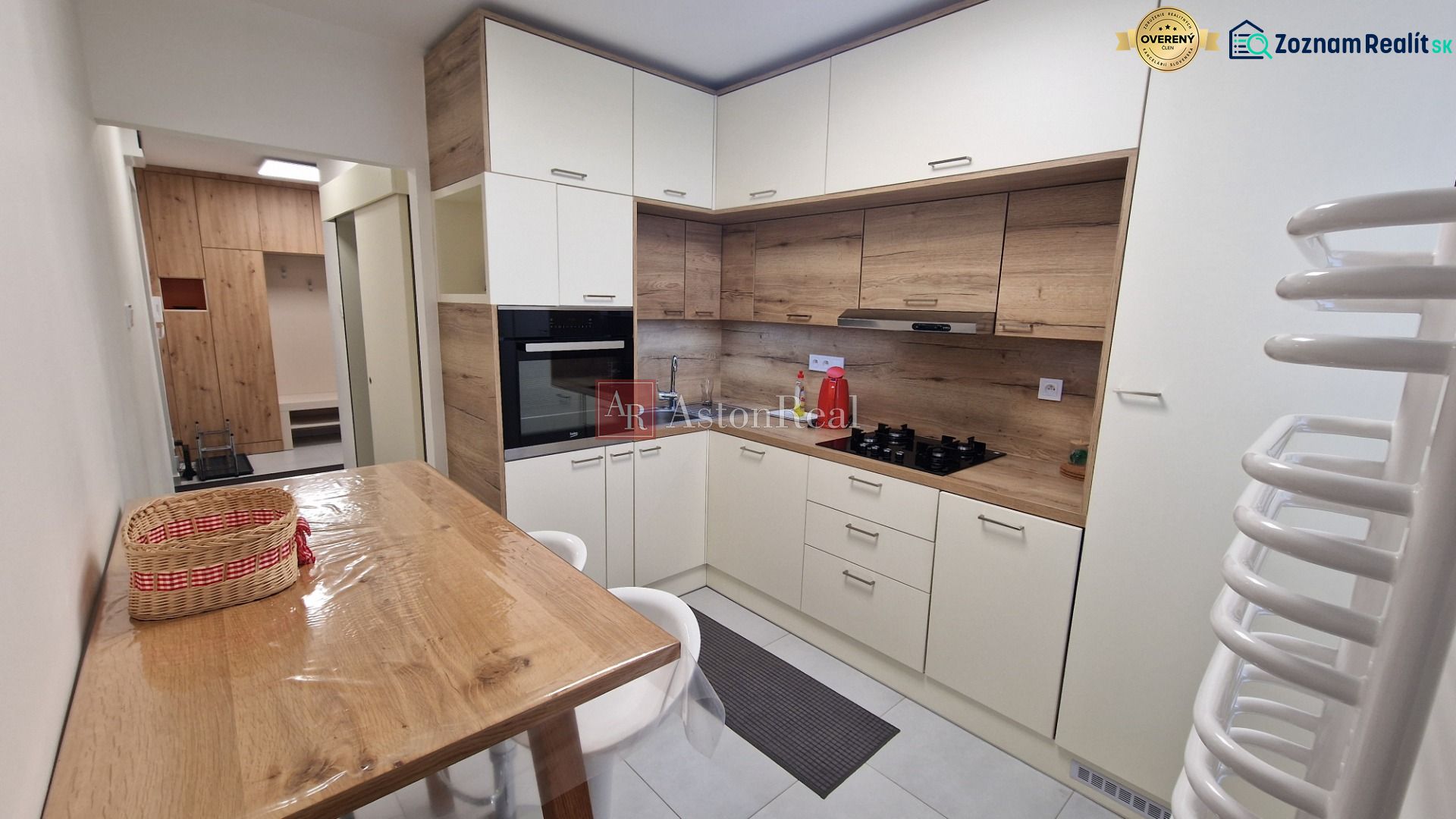 A kitchen in a 3-room apartment with a corner unit and flooring with a wood decor.