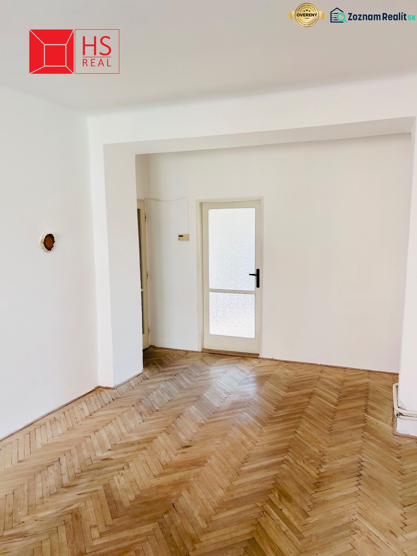 A room with a wooden decor floor and glass doors in a two-room apartment.