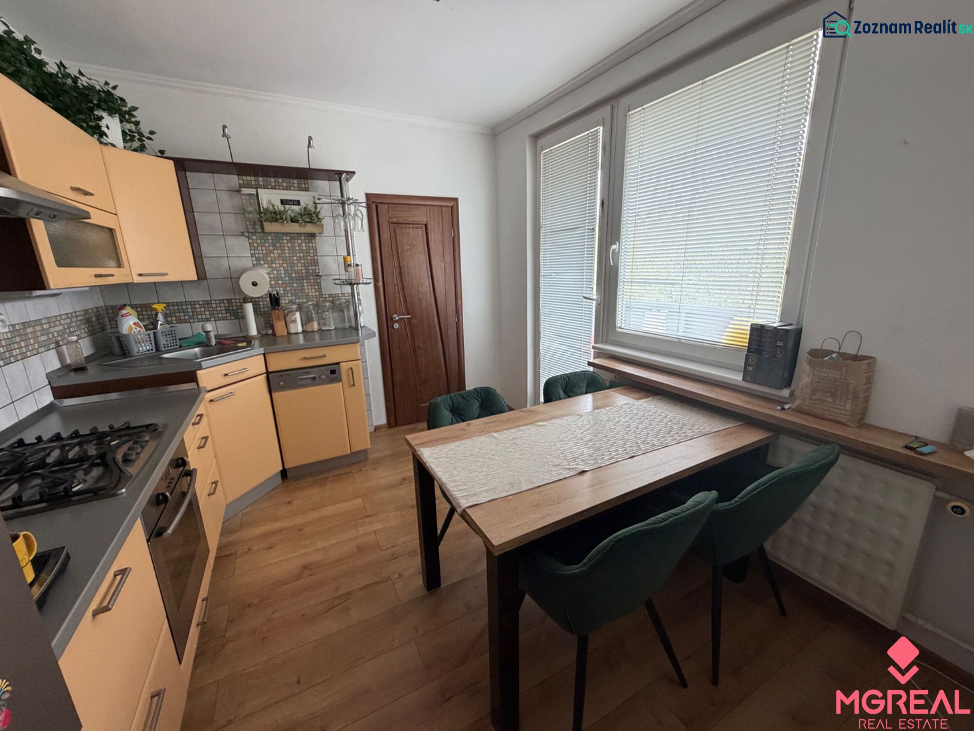 A kitchen in a 3-room apartment with a corner unit and a floor with a wood decor.