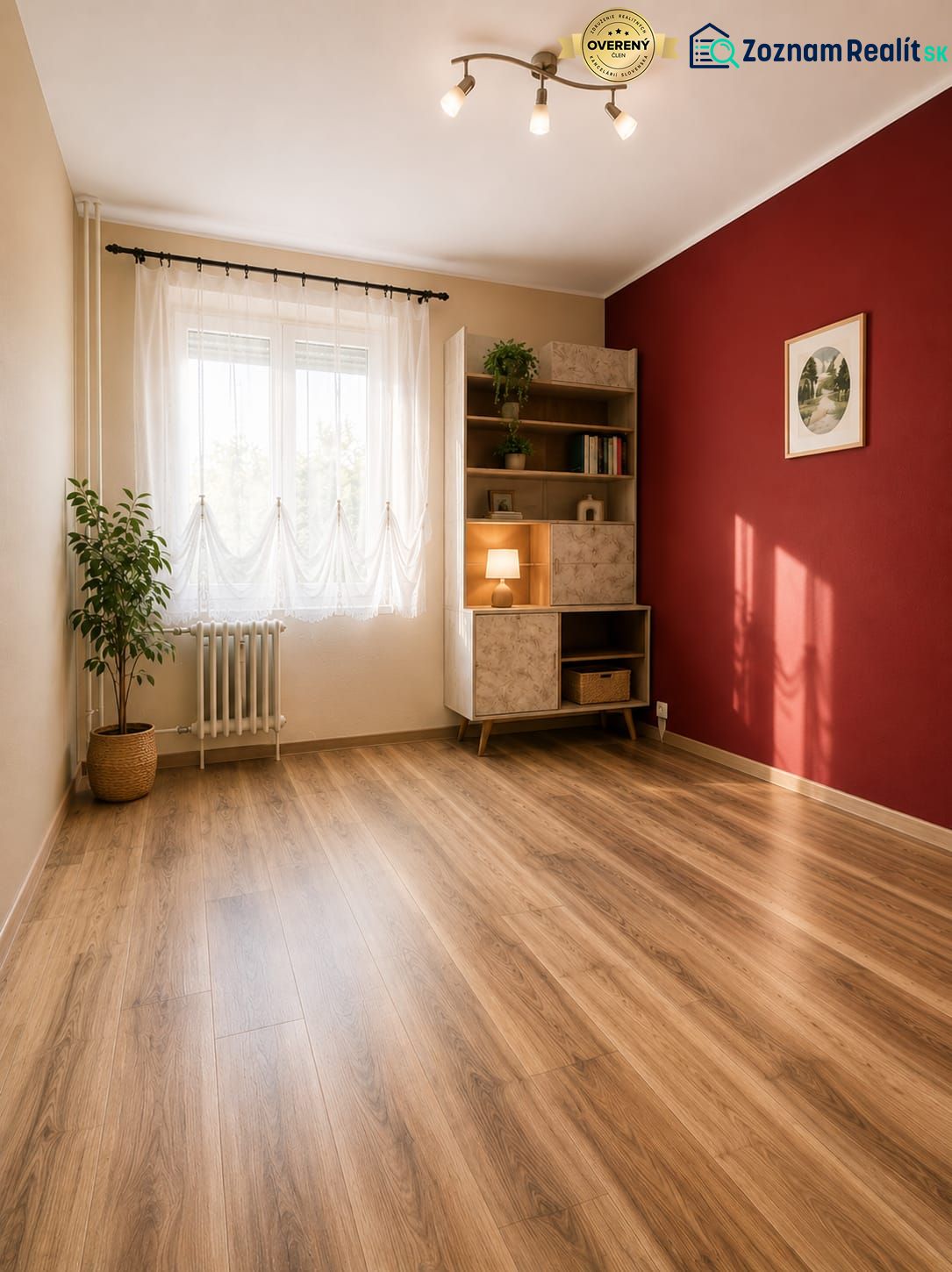 A room in a 3-room apartment with a wooden decor floor, a red wall, and a shelving cabinet.