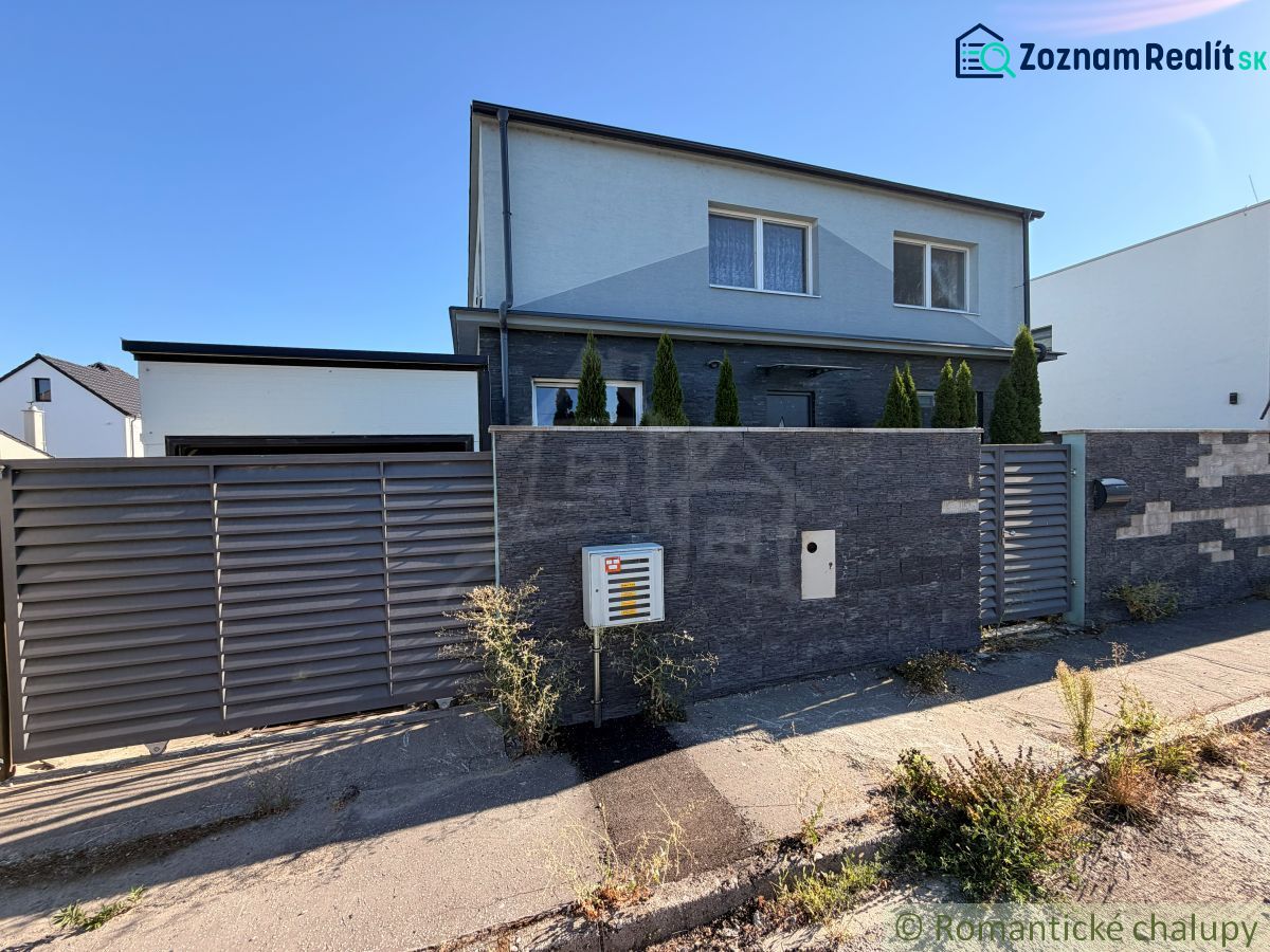 A family house in Komárno with a modern fence and landscaping with plants at the entrance.