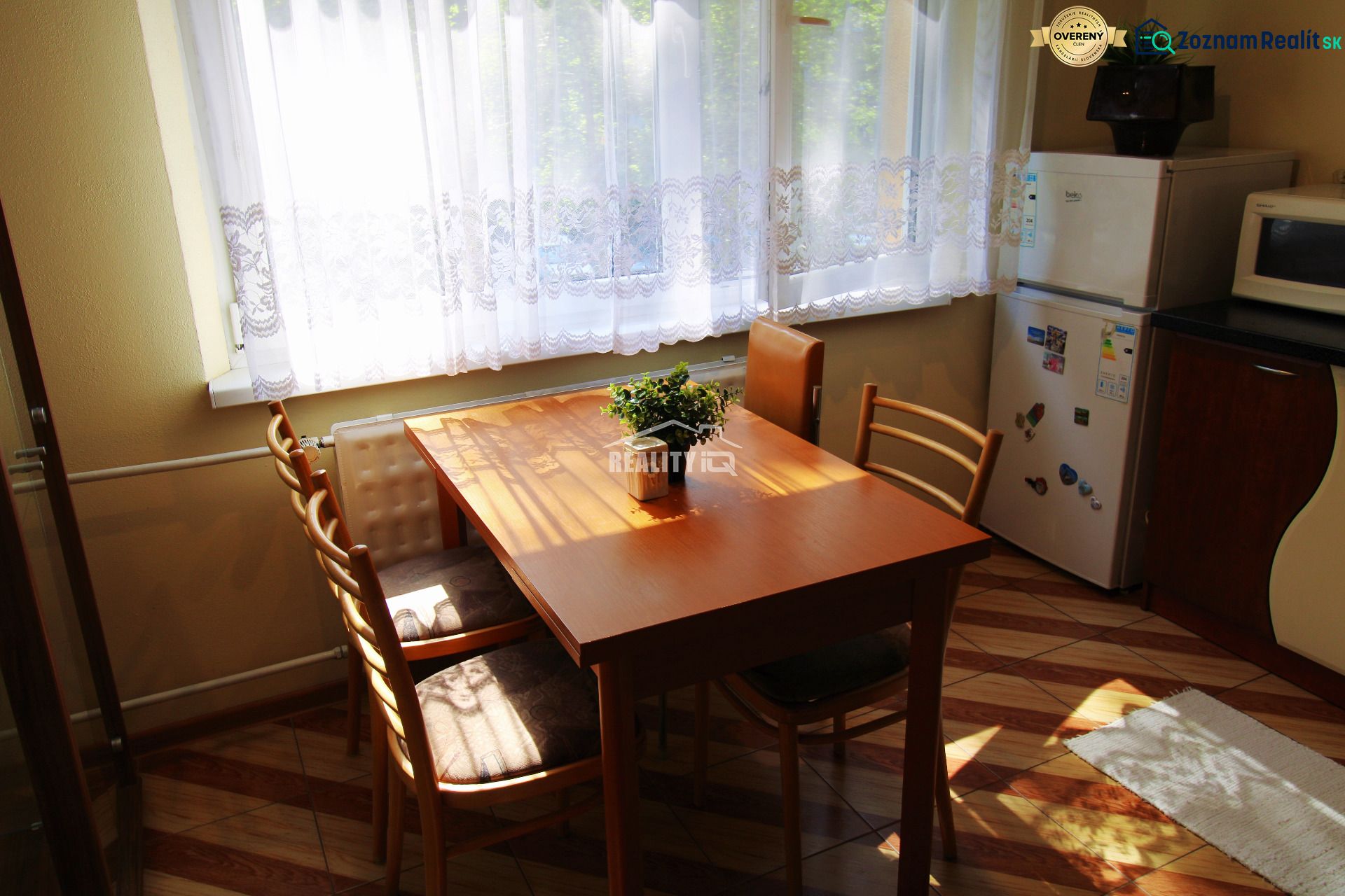 Dining area with a wooden table and chairs in a studio apartment with a view of greenery.