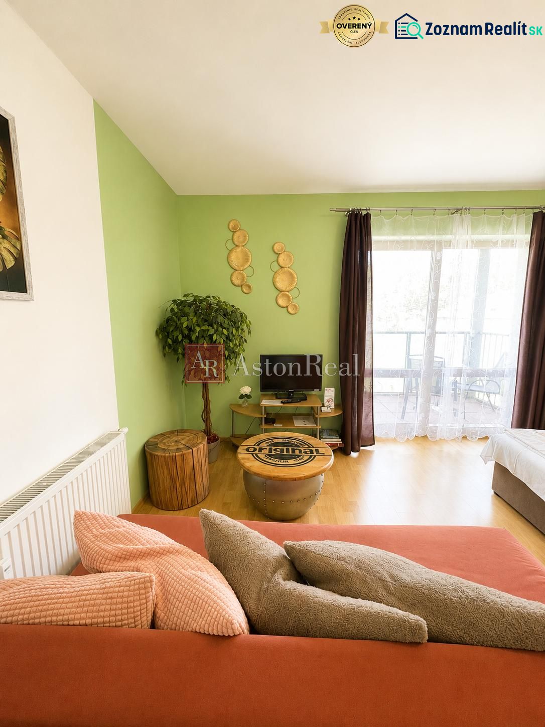 Living room of a one-bedroom apartment with a wooden decor floor, green wall, comfortable sofa.