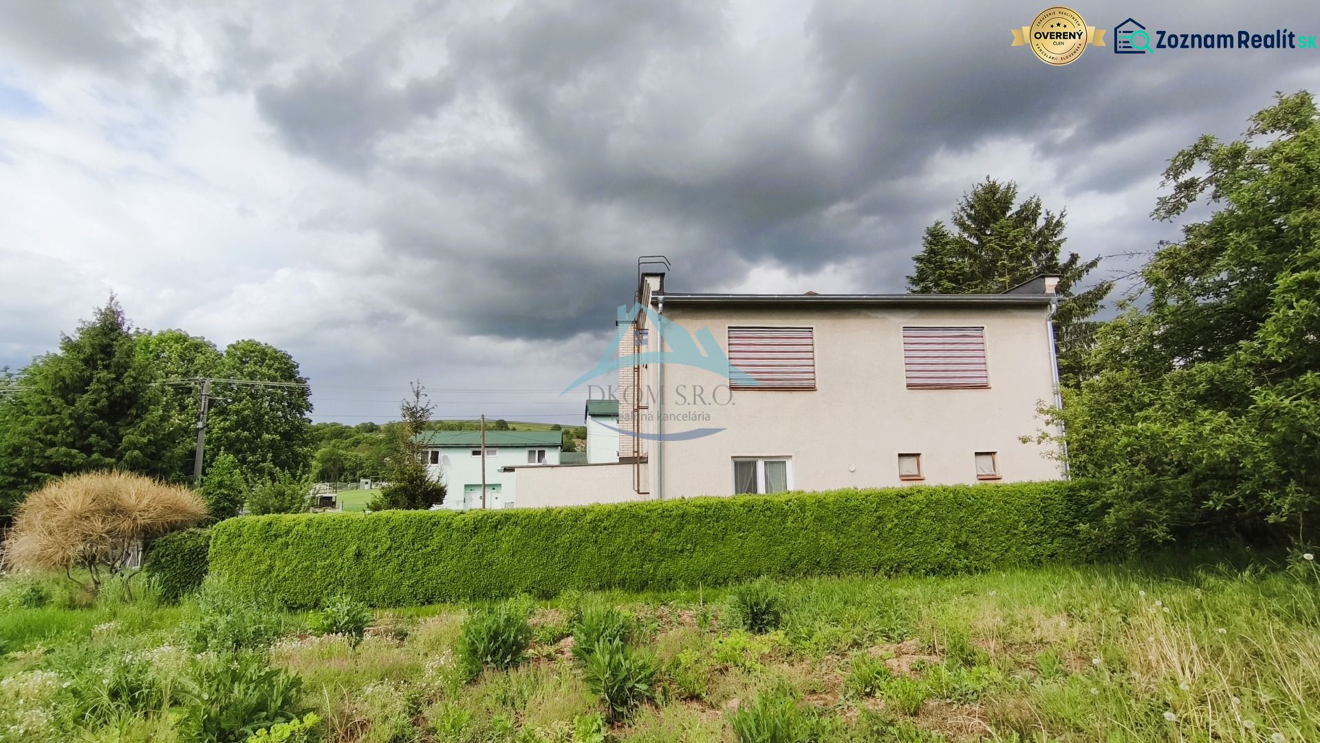 A family house in Nenince surrounded by dense greenery and trees under a cloudy sky.