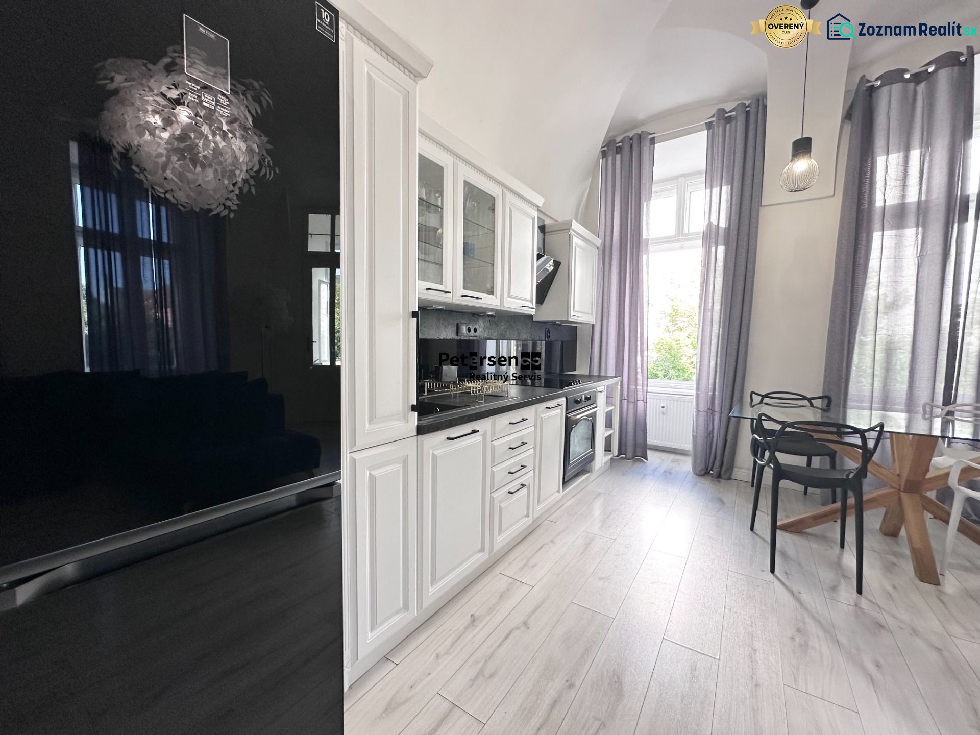 A spacious kitchen with white furniture and a floor with a wood decor in a 3-room apartment.