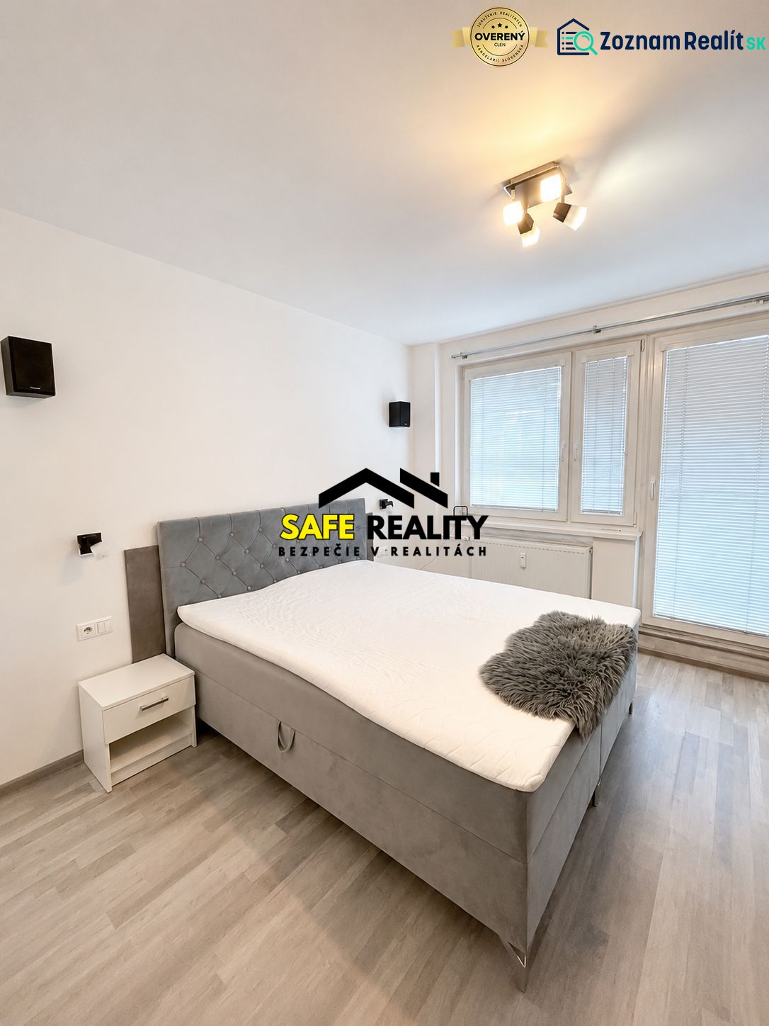 A bedroom with a double bed, wooden decor flooring, and a window in a three-room apartment.
