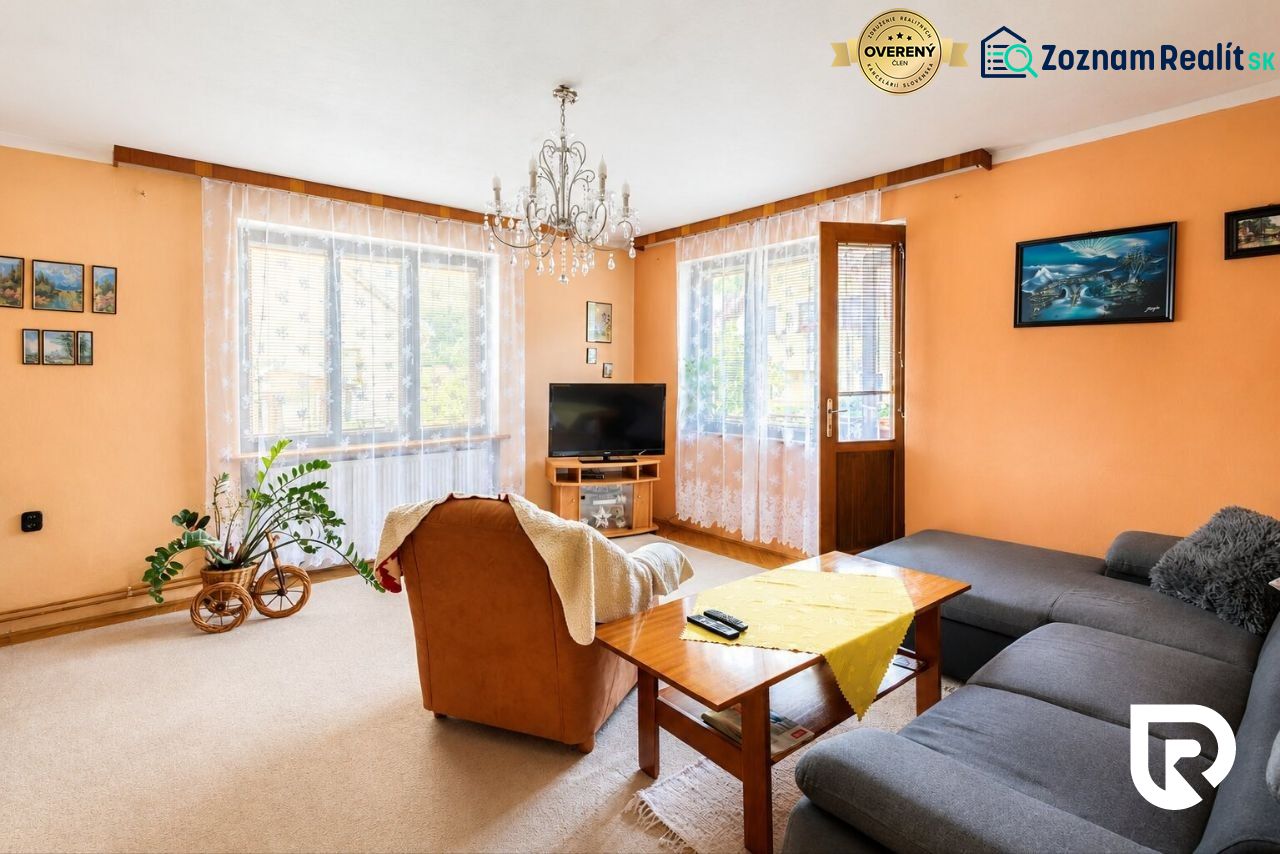Living room with cream walls, an orange armchair, and a gray sofa in a family house.