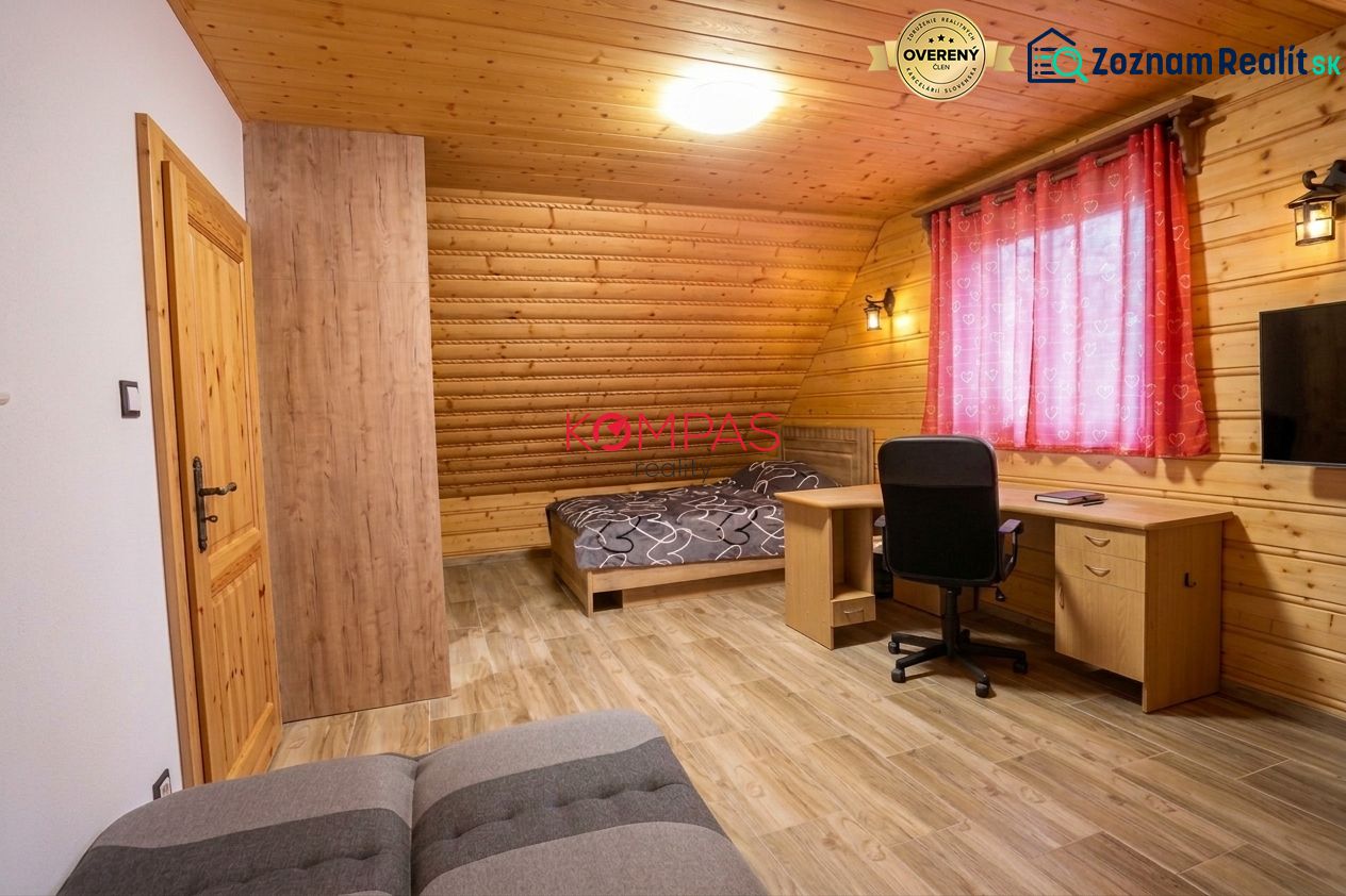 A room in a family house with wooden walls, a floor with a wooden decor, and a work desk.