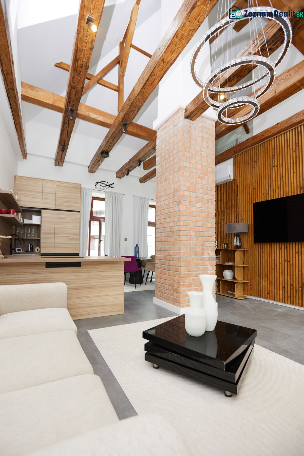 Living room in a 3-room apartment with exposed beams and a brick pillar.