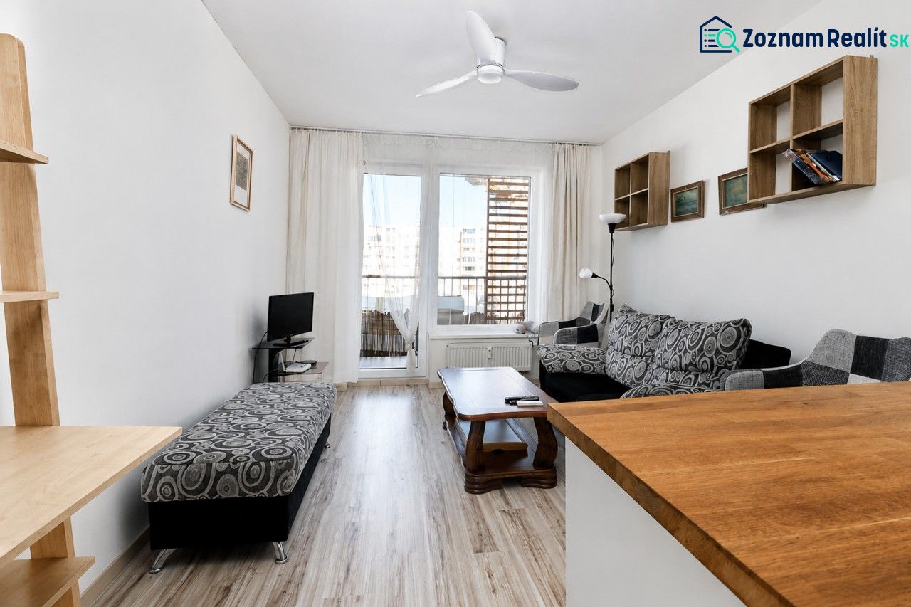 Living room with wood-patterned flooring, a sofa, and a television in a two-room apartment.