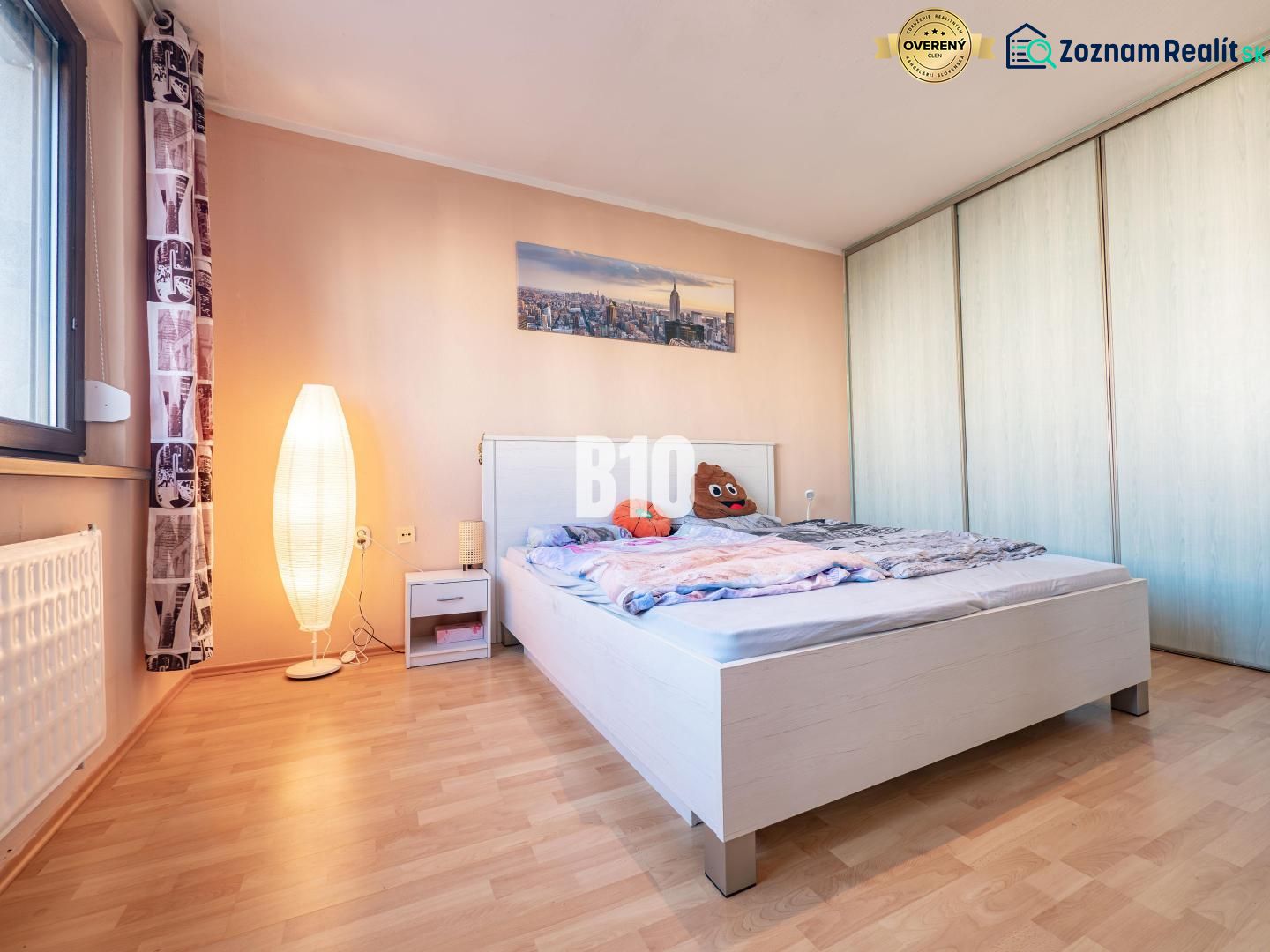 A bedroom with wood-patterned flooring, a bed, and a wardrobe in a studio apartment.