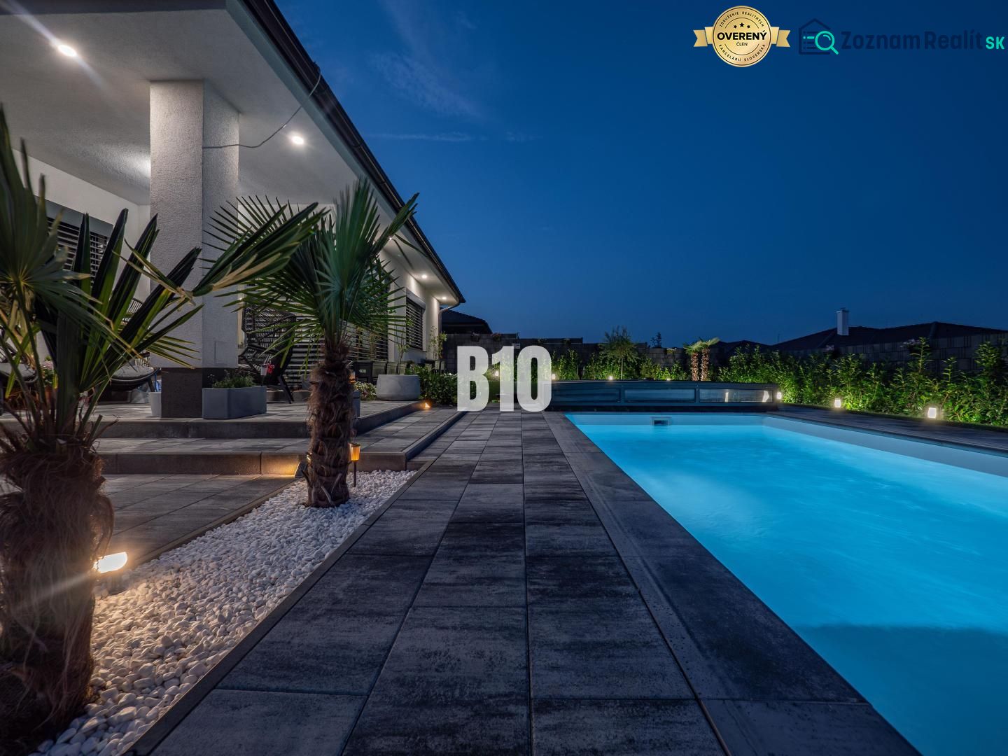 A family house in Nitra with a swimming pool and an illuminated garden in the evening.