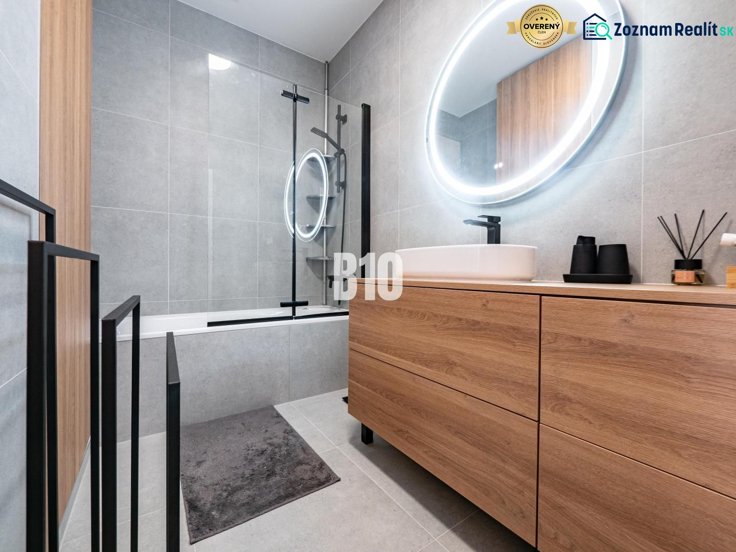 A bathroom with wooden decor in a family house, featuring a bathtub and an oval mirror with lighting.