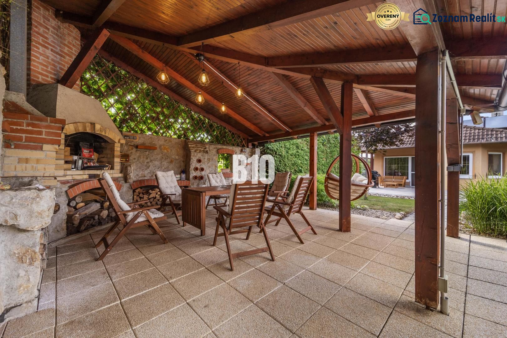 A covered terrace with a fireplace and wooden chairs at a family house in Nitra.