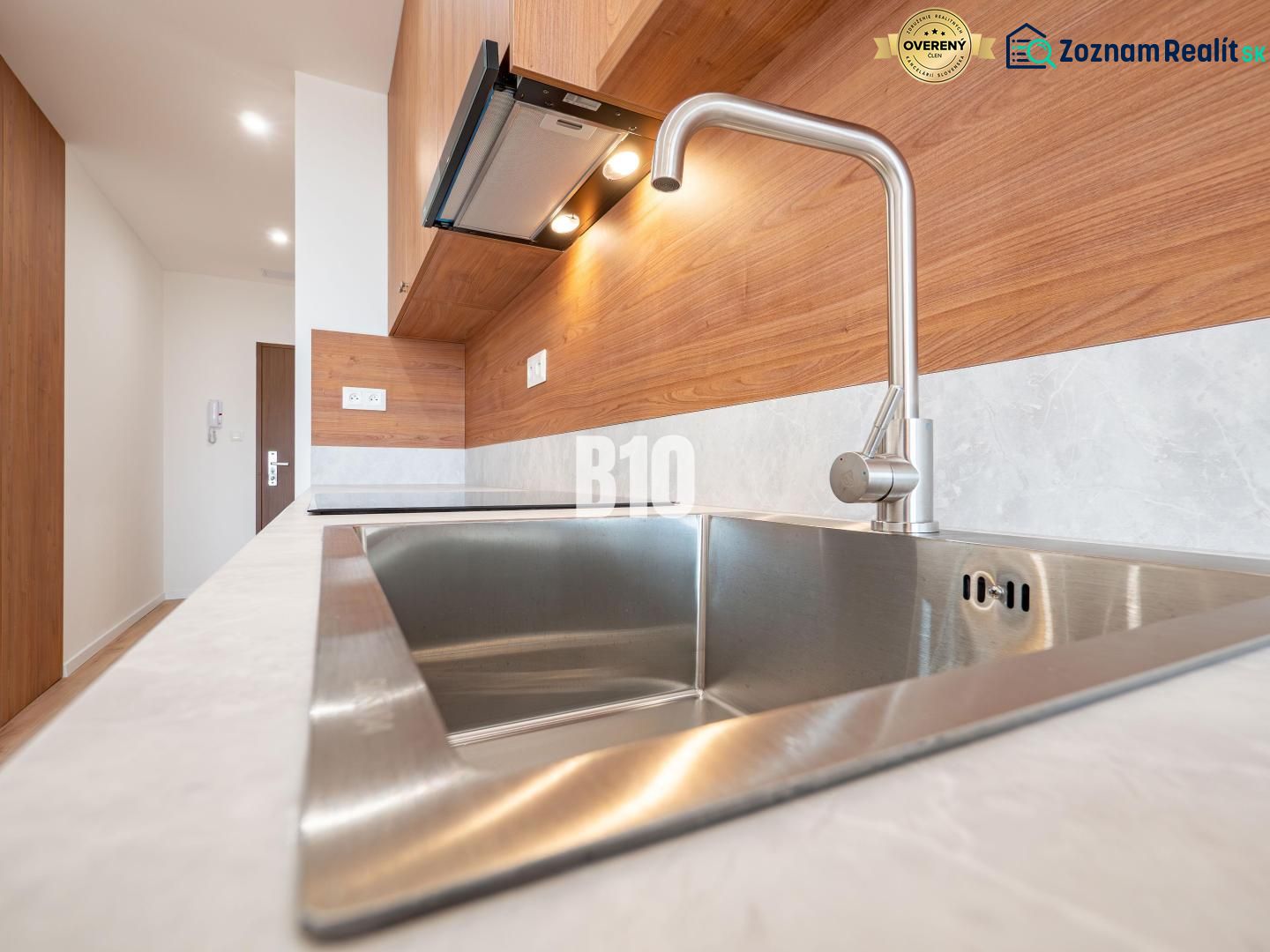 Modern kitchen in a 3-room apartment with a stainless steel sink and wooden decor.