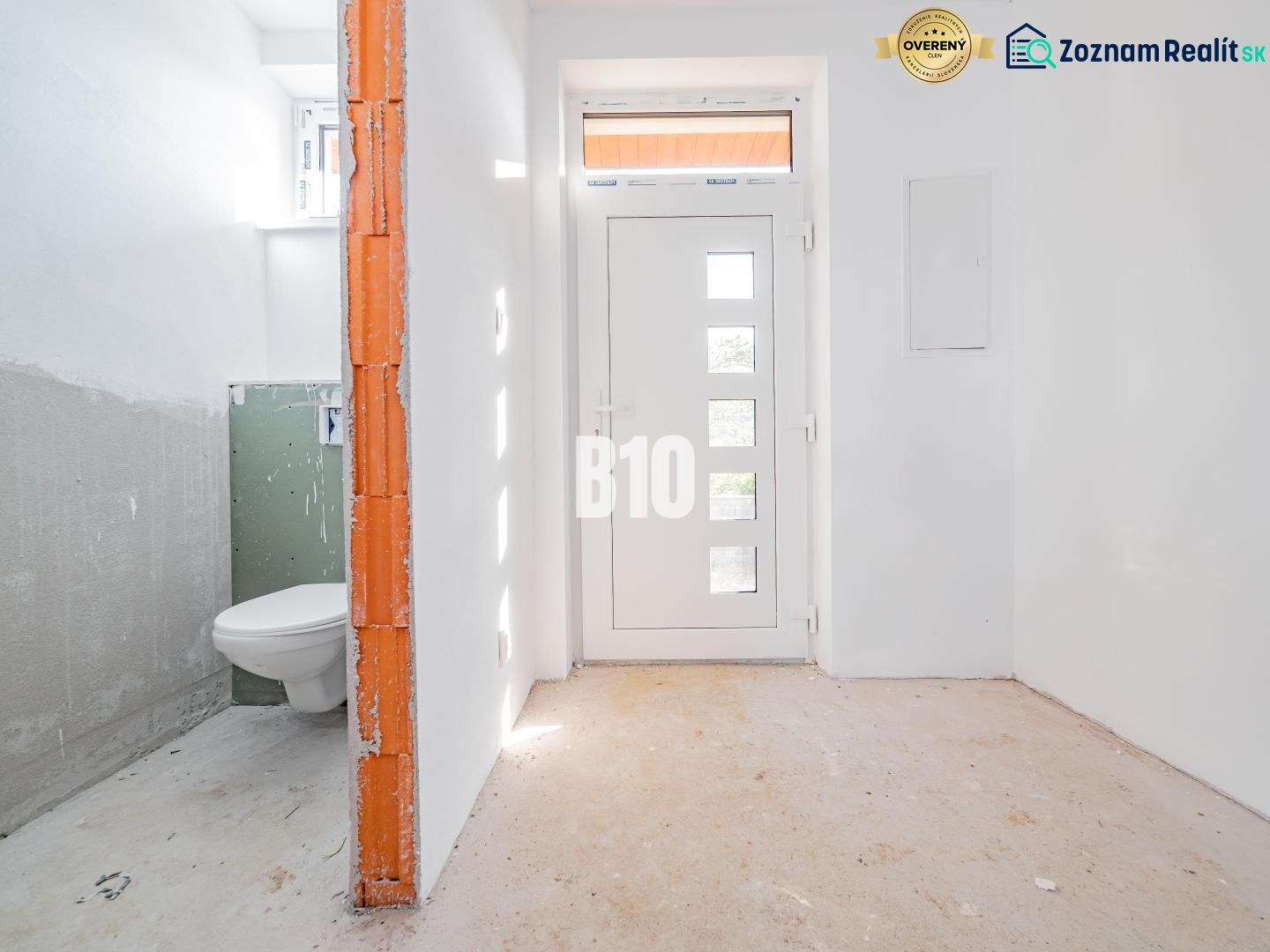 White hallway of a family house with entrance doors and a bathroom on the left.
