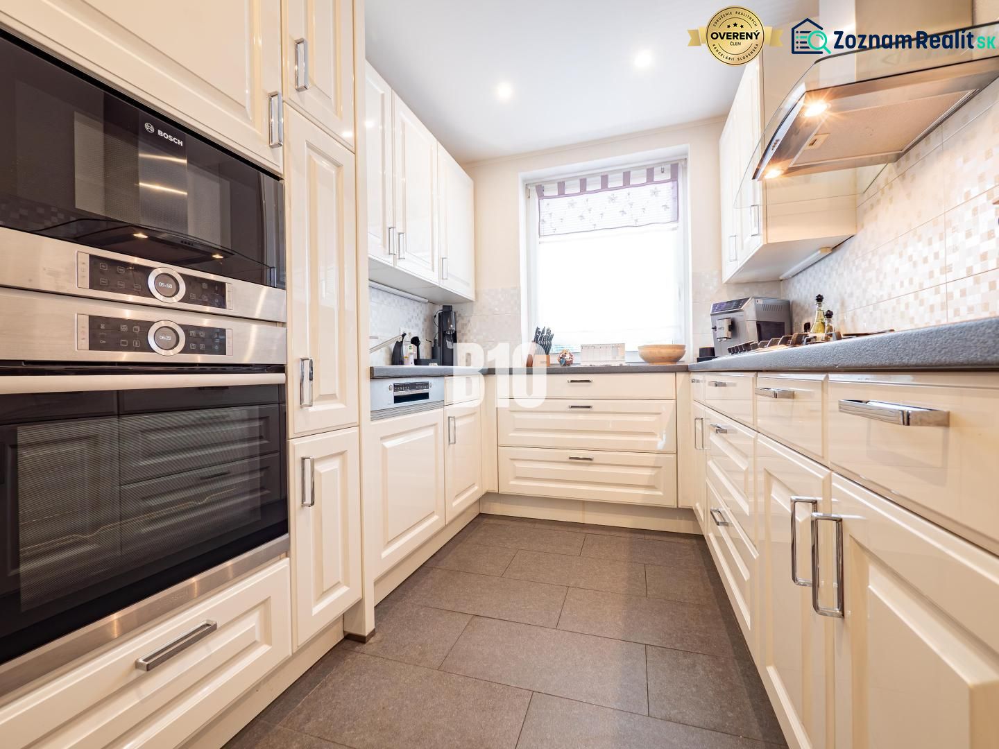 A kitchen with white cabinets and appliances, a wood-decor floor, in a family house.