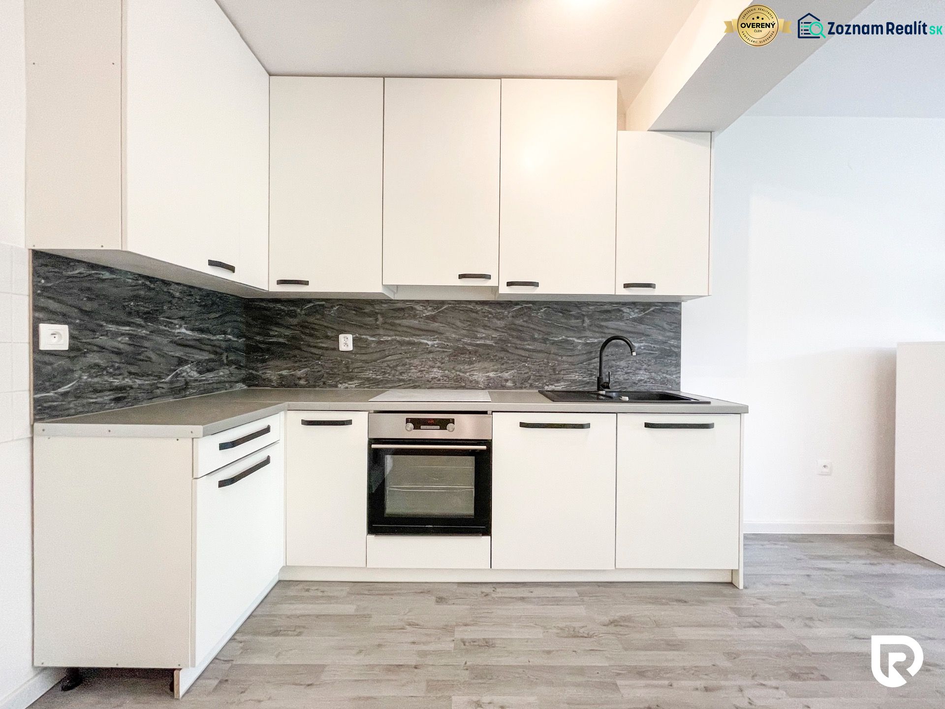 A kitchen unit with a black sink in a 2-room apartment, floor with a wooden decor.