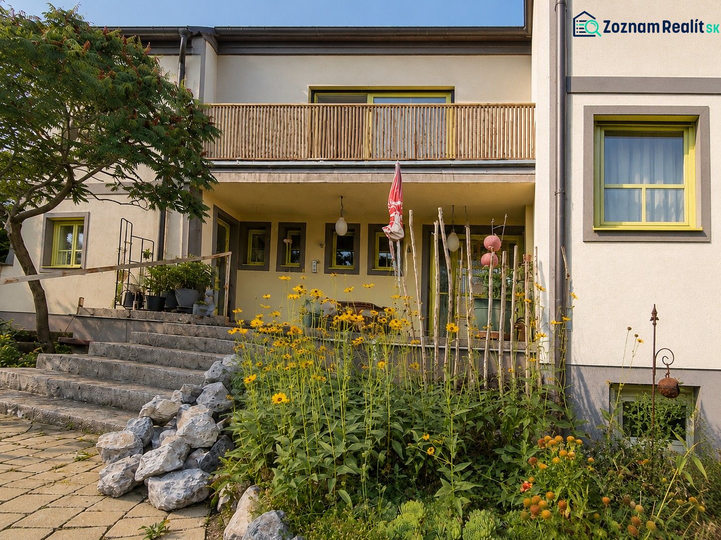 A family house in Podersdorf am See with stone stairs and a garden full of flowers.
