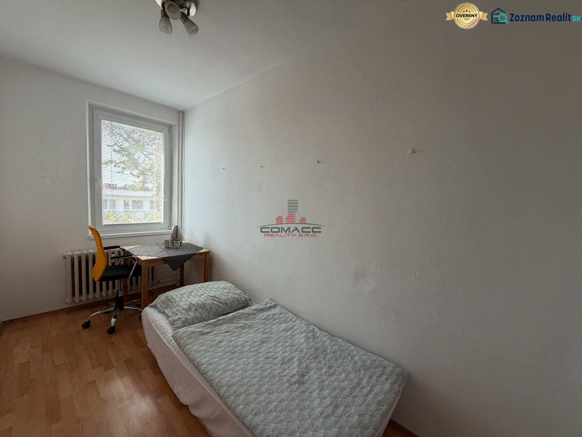A room in a 3-room apartment with a bed, a table, and a floor with a wooden decor.