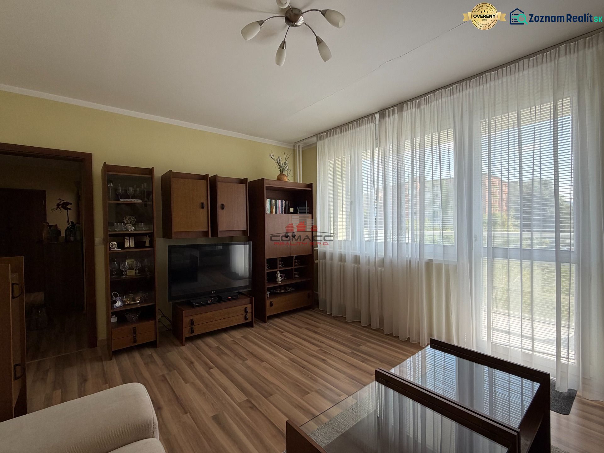 Living room in a three-room apartment with a wooden decor floor and large windows.