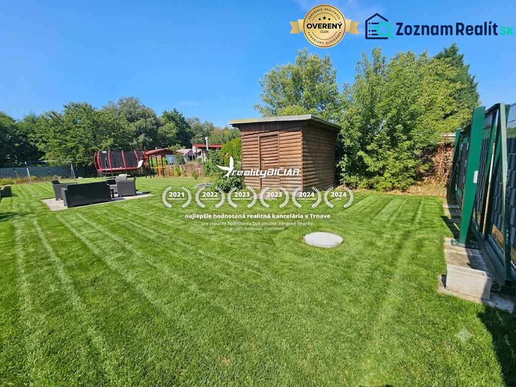 Grassy gardens in Kamenný mlyn in Trnava with a wooden shelter and a trampoline.