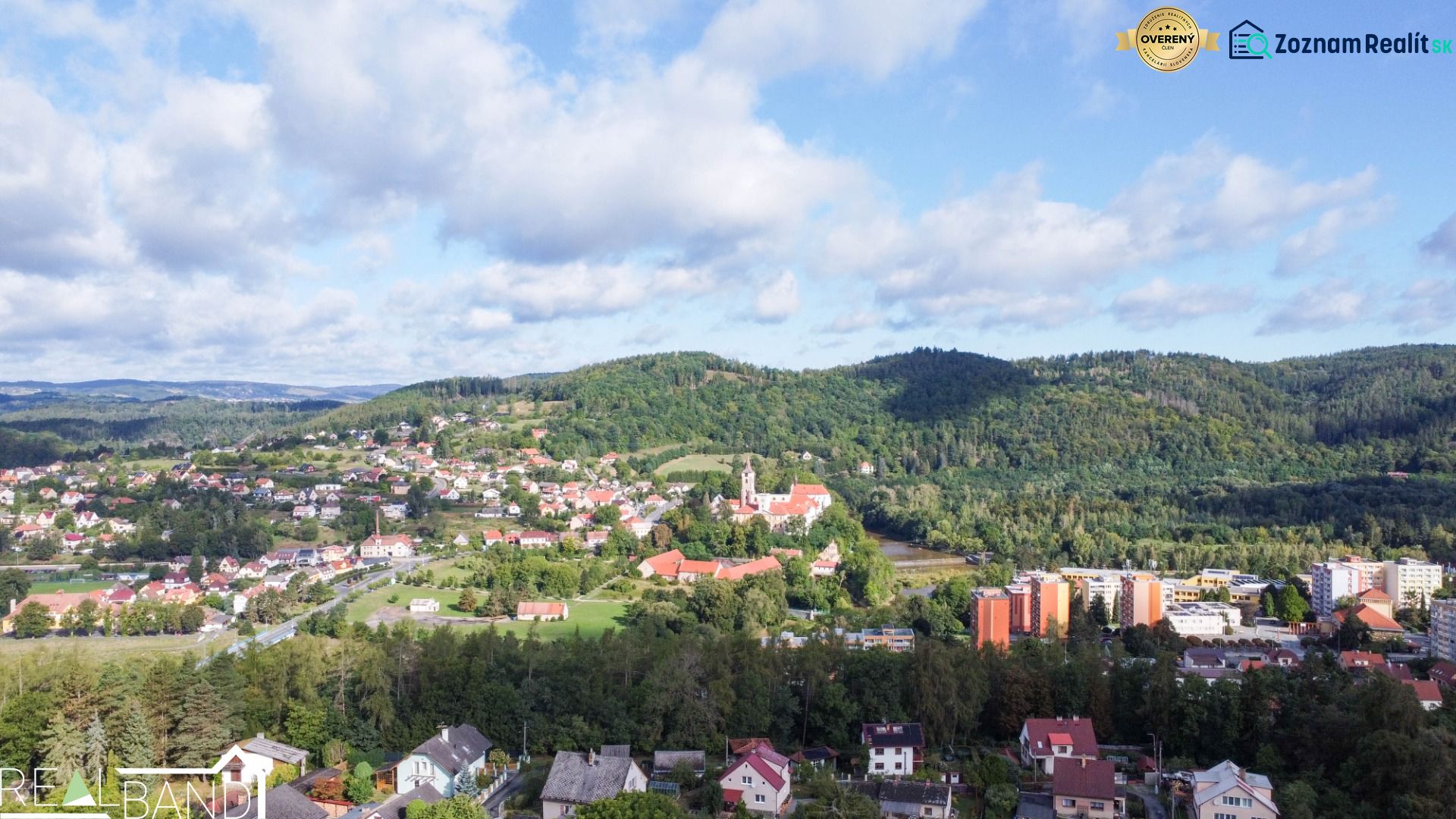 A view of the town of Sázava from Na Vrších Street, surrounded by greenery and family houses.