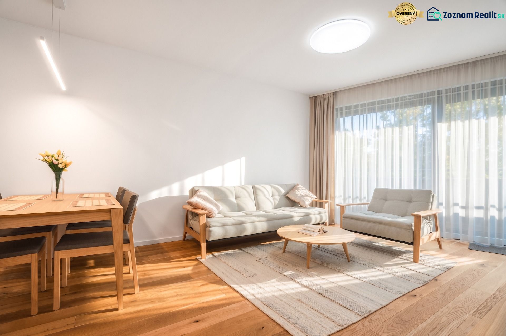 A bright living room with wood-patterned flooring, a sofa, and a dining table.