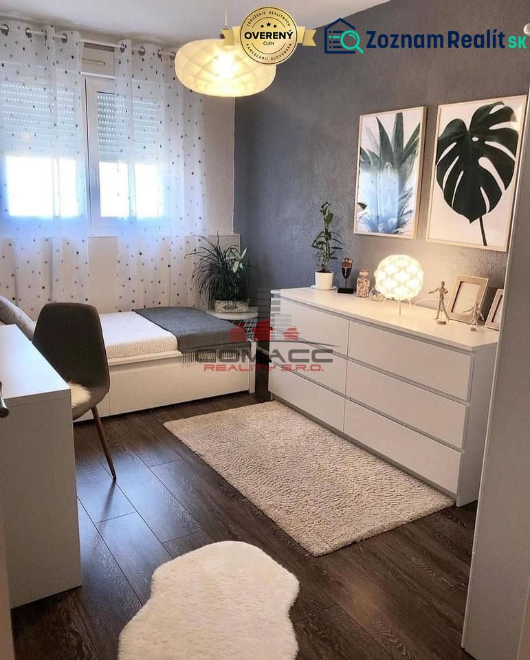 A room in a family house with a wooden decor floor, artistic paintings, and decorative flowers.
