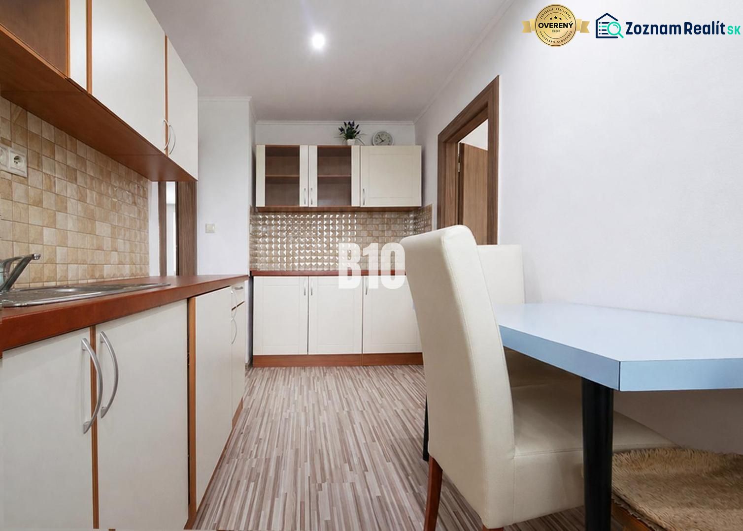 A kitchen in a 3-room apartment with a wooden decor floor and light furniture.