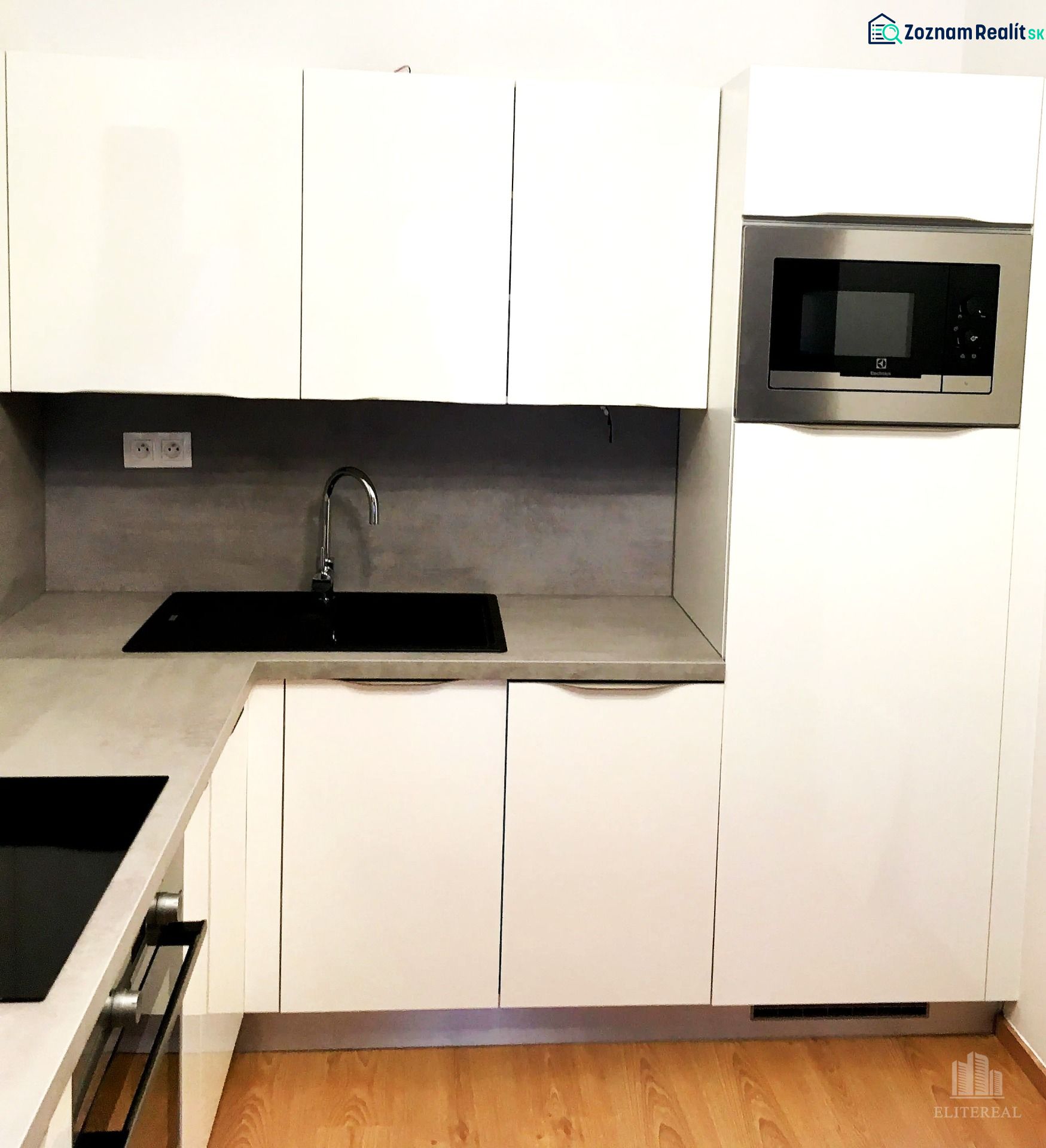 White kitchen with a microwave and built-in sink, 2-room apartment, floor with wood decor.