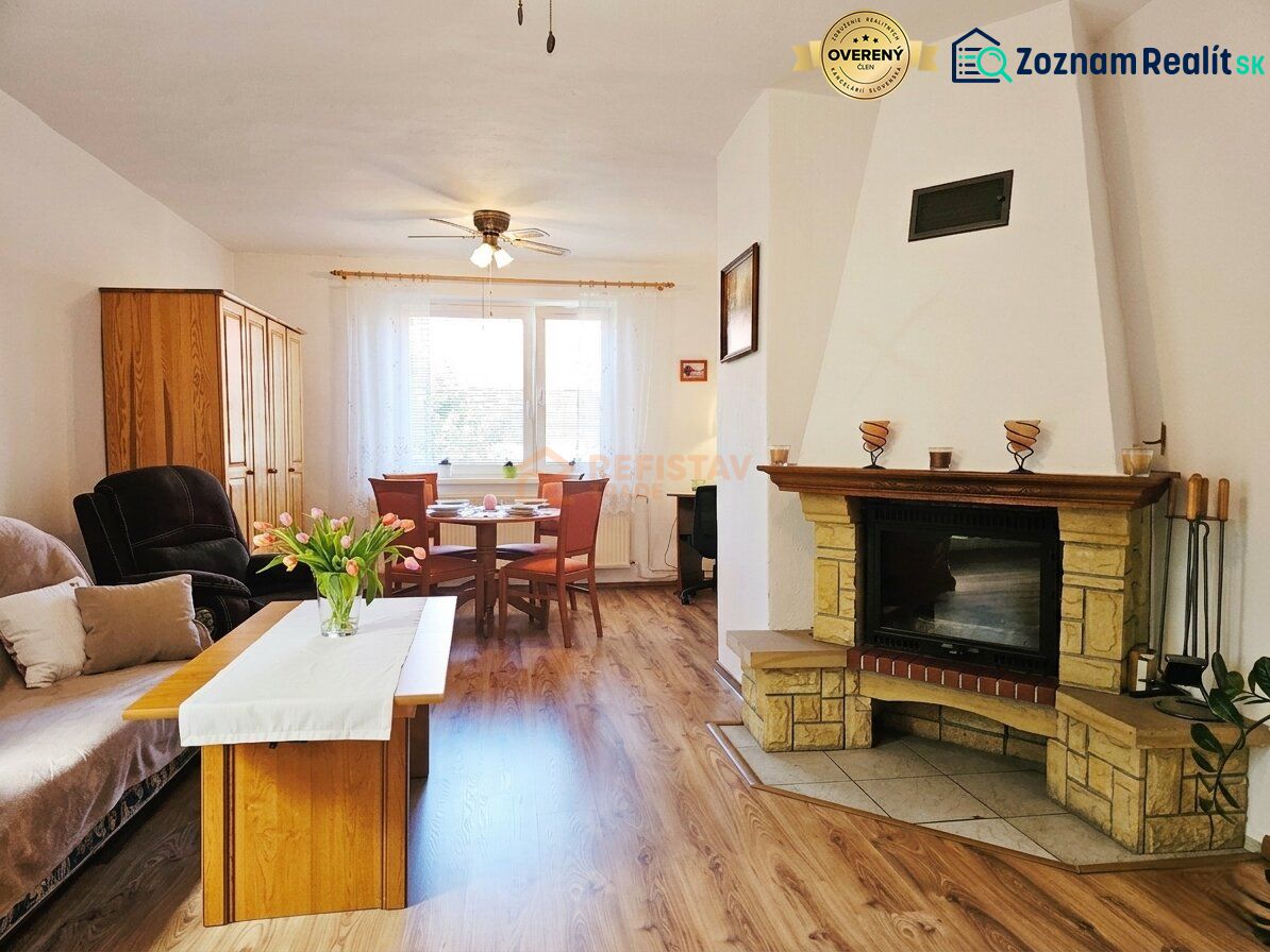 A room in a family house with a fireplace, a sofa set, and a floor with a wooden decor.