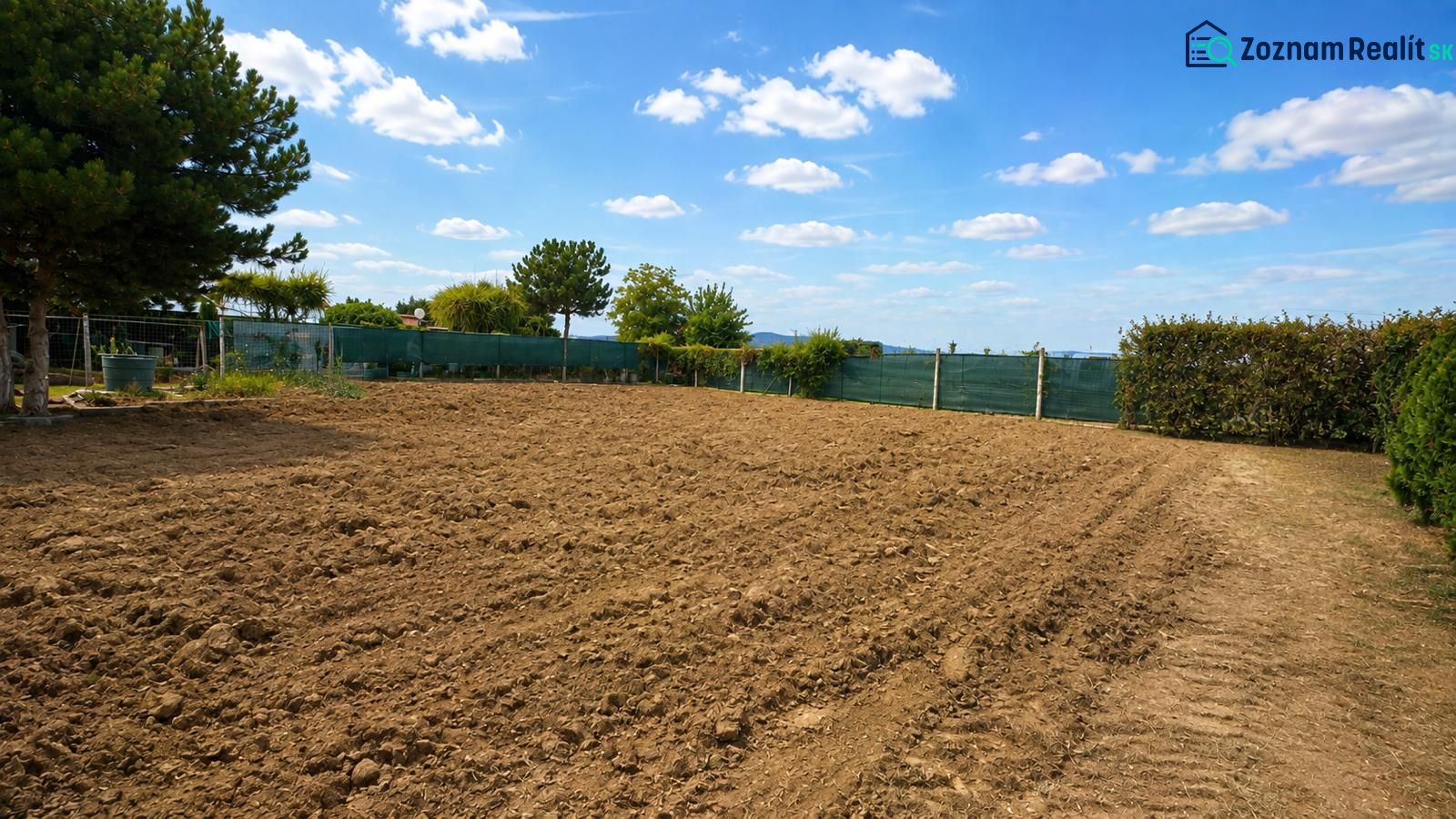 Residential plots in Pravotice with cultivated land, green hedges, and blue skies.