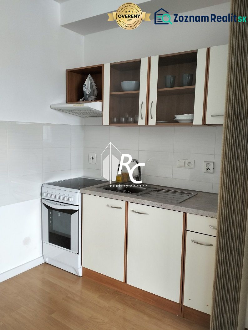 A kitchen with white cabinets in a two-room apartment, a floor with a wooden decor.