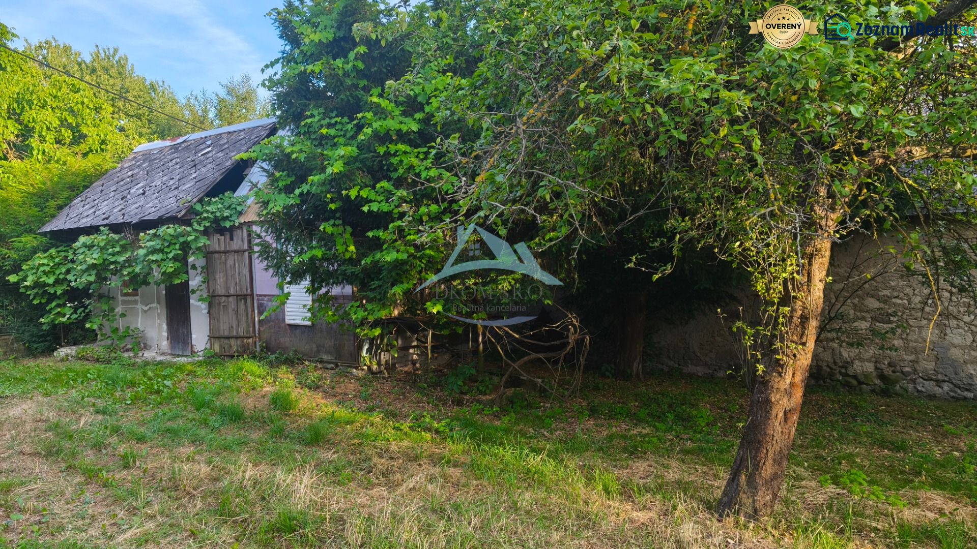 A family house in Čelovce, surrounded by greenery and trees, with an older shelter.