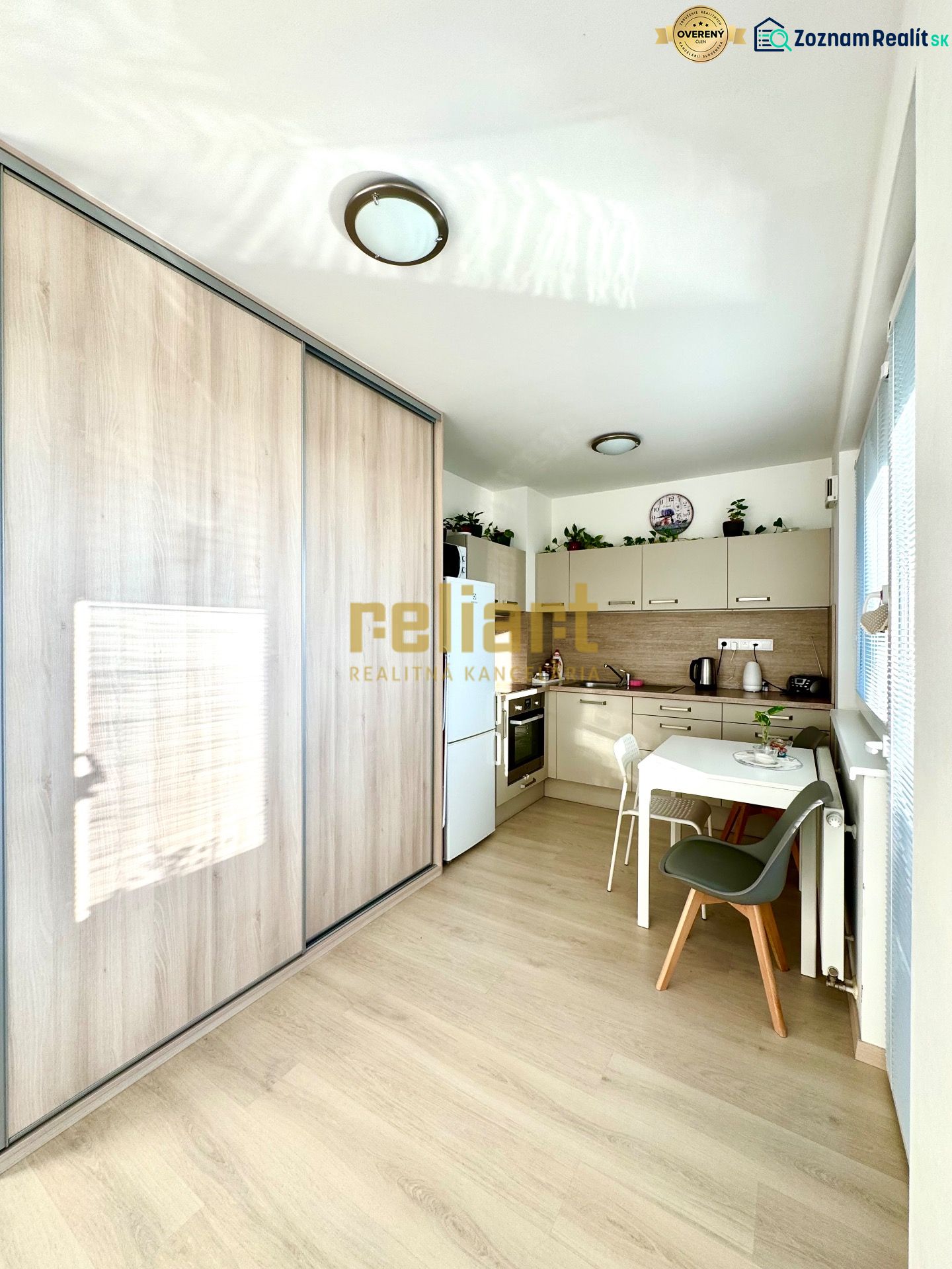 A kitchen corner with a wooden decor floor and a built-in wardrobe in a studio apartment.