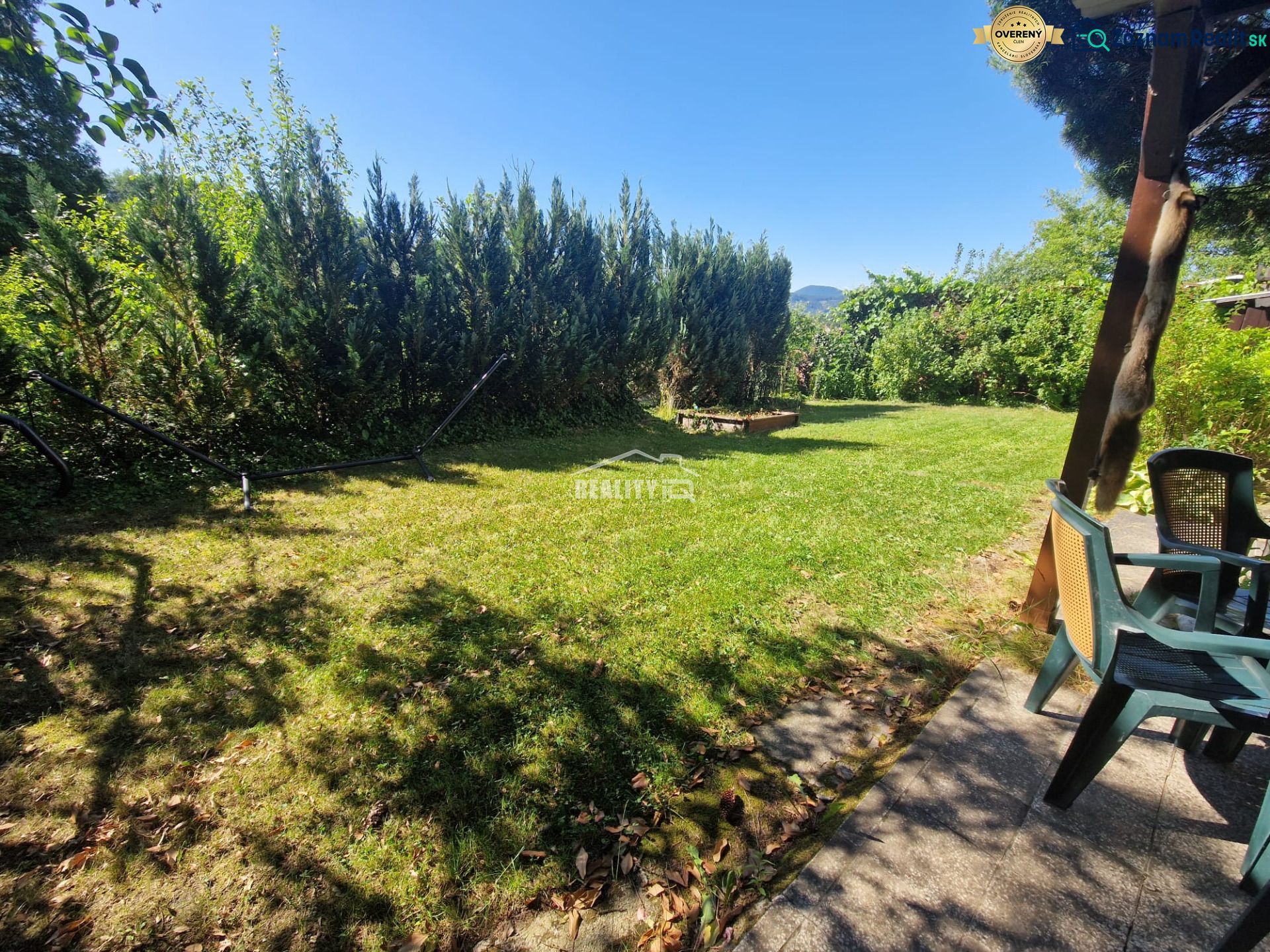 Garden space in Žilina near the cottage with chairs and greenery, surrounded by trees.