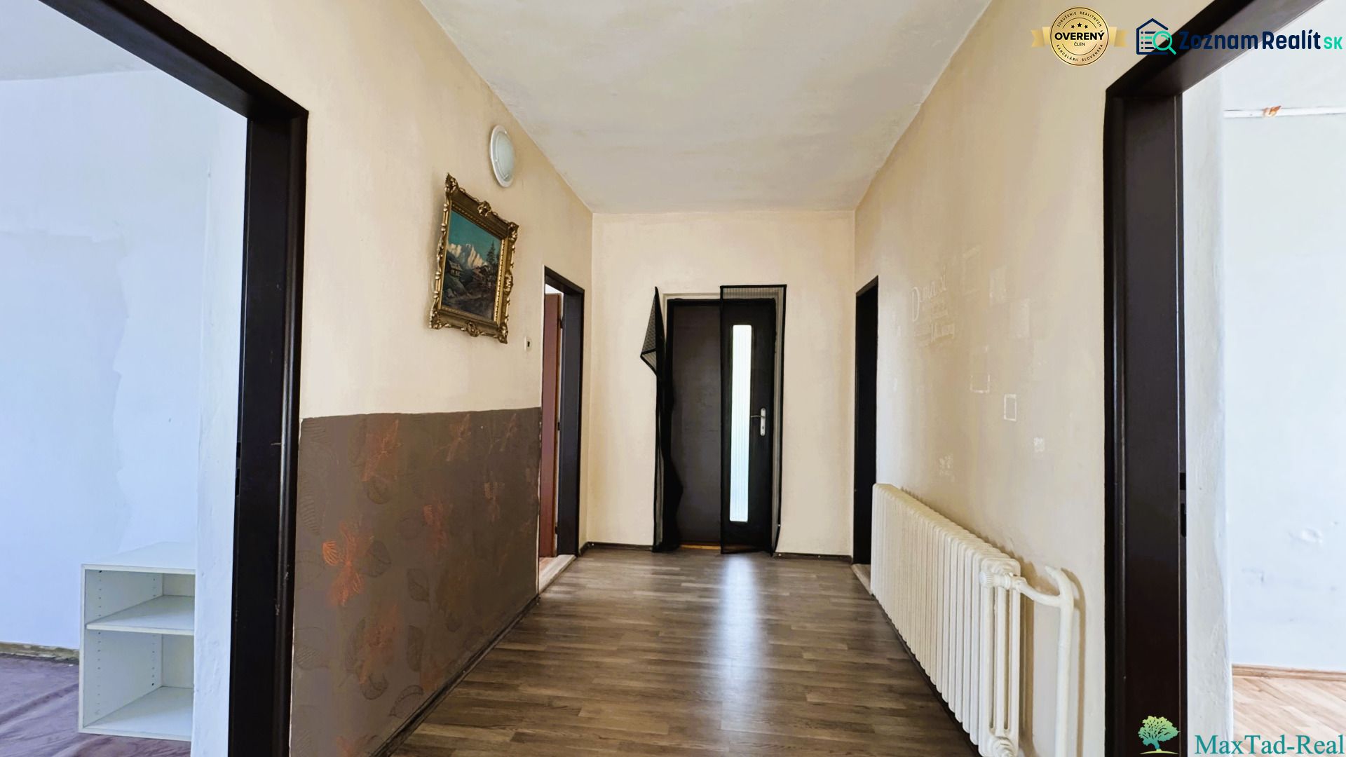 A hallway in a family house with a wooden decor floor and a painting on the wall.